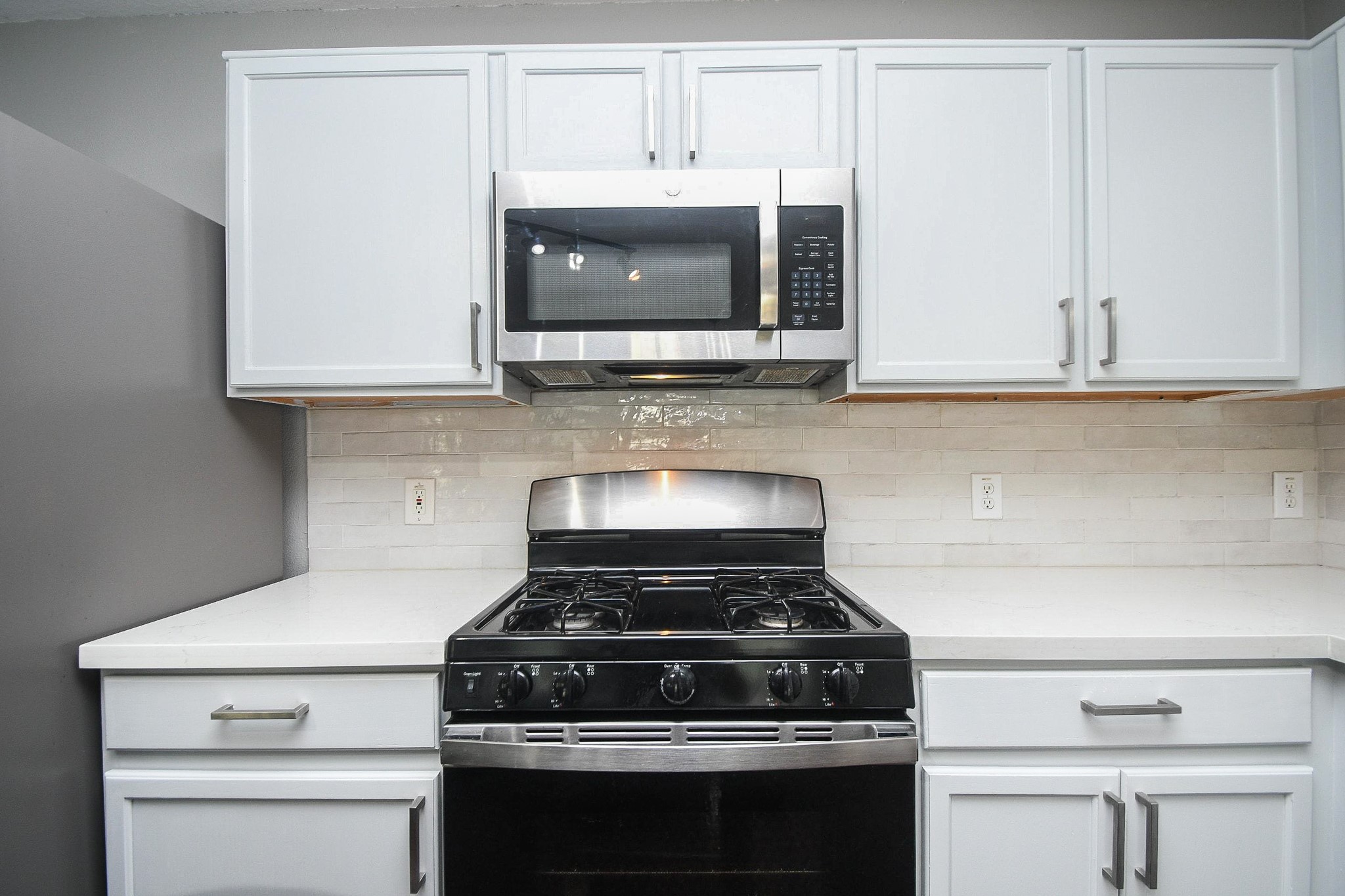 Modern kitchen featuring sleek stainless steel appliances, pristine white cabinetry, and a stylish subway tile backsplash.