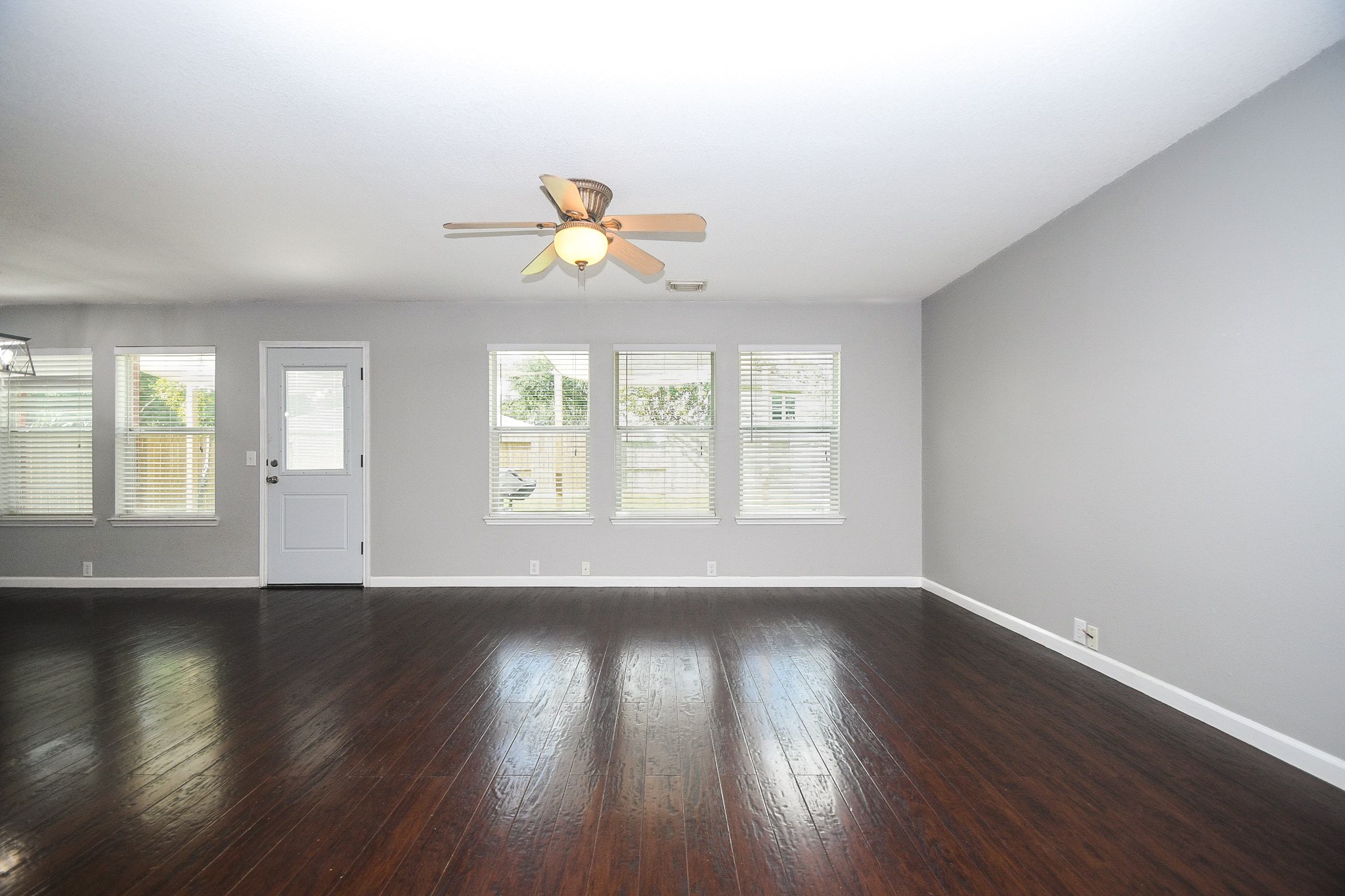 Spacious living area with abundant natural light from multiple windows, and a ceiling fan for comfort.
