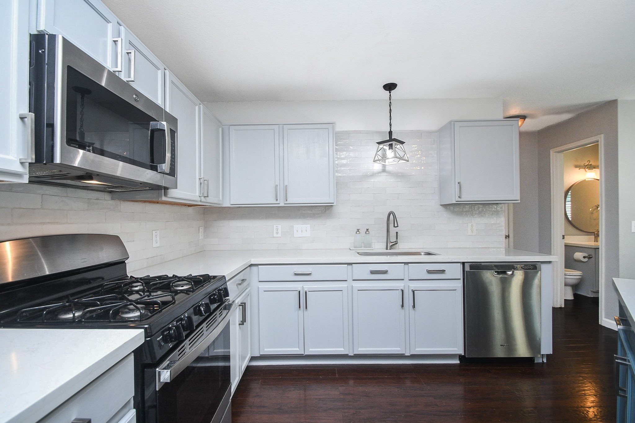 Sleek kitchen with modern stainless steel appliances, elegant white cabinetry, and a stylish tile backsplash.
