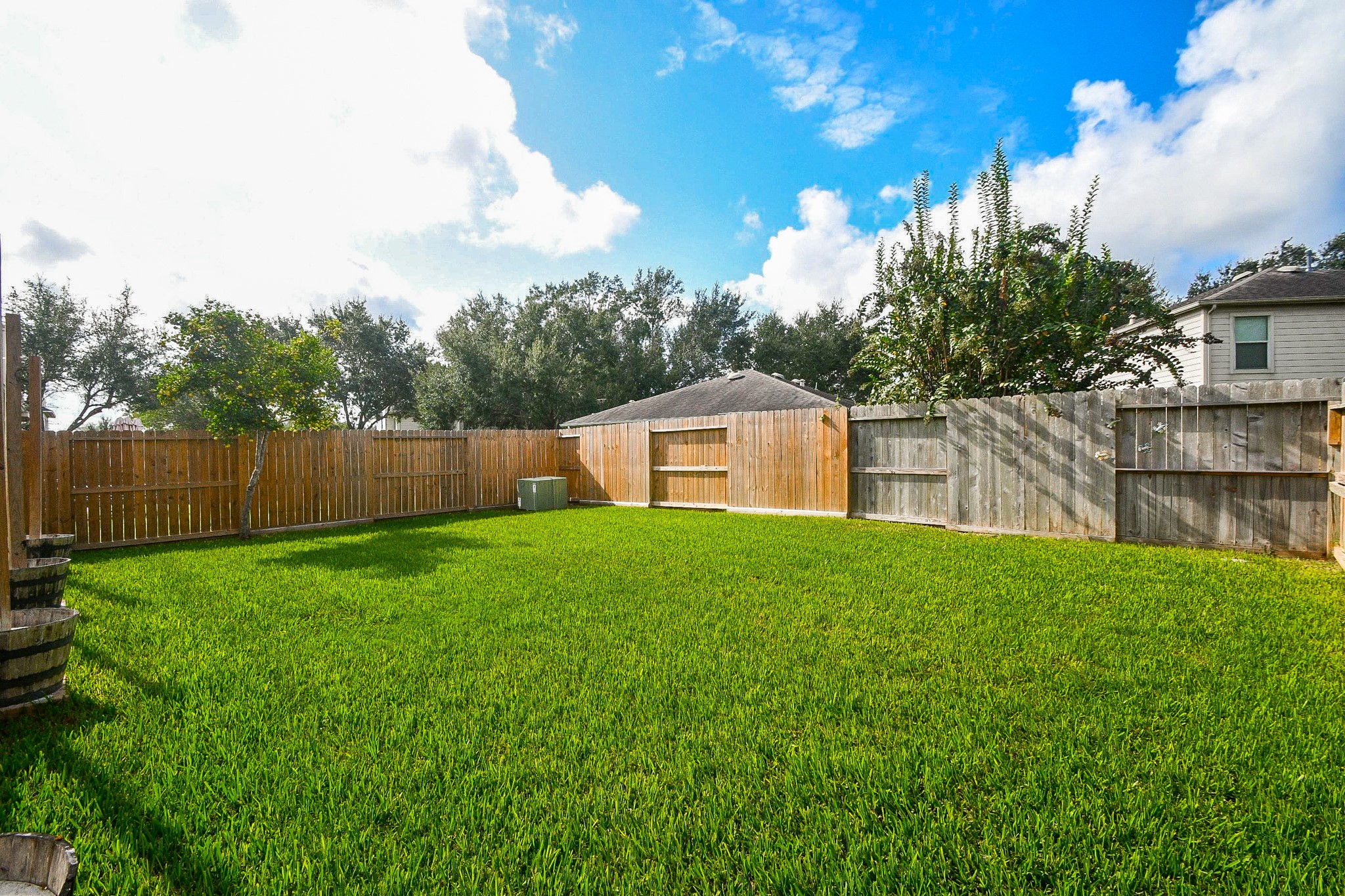 Spacious backyard with lush green lawn, perfect for outdoor activities, surrounded by a secure wooden fence for privacy.