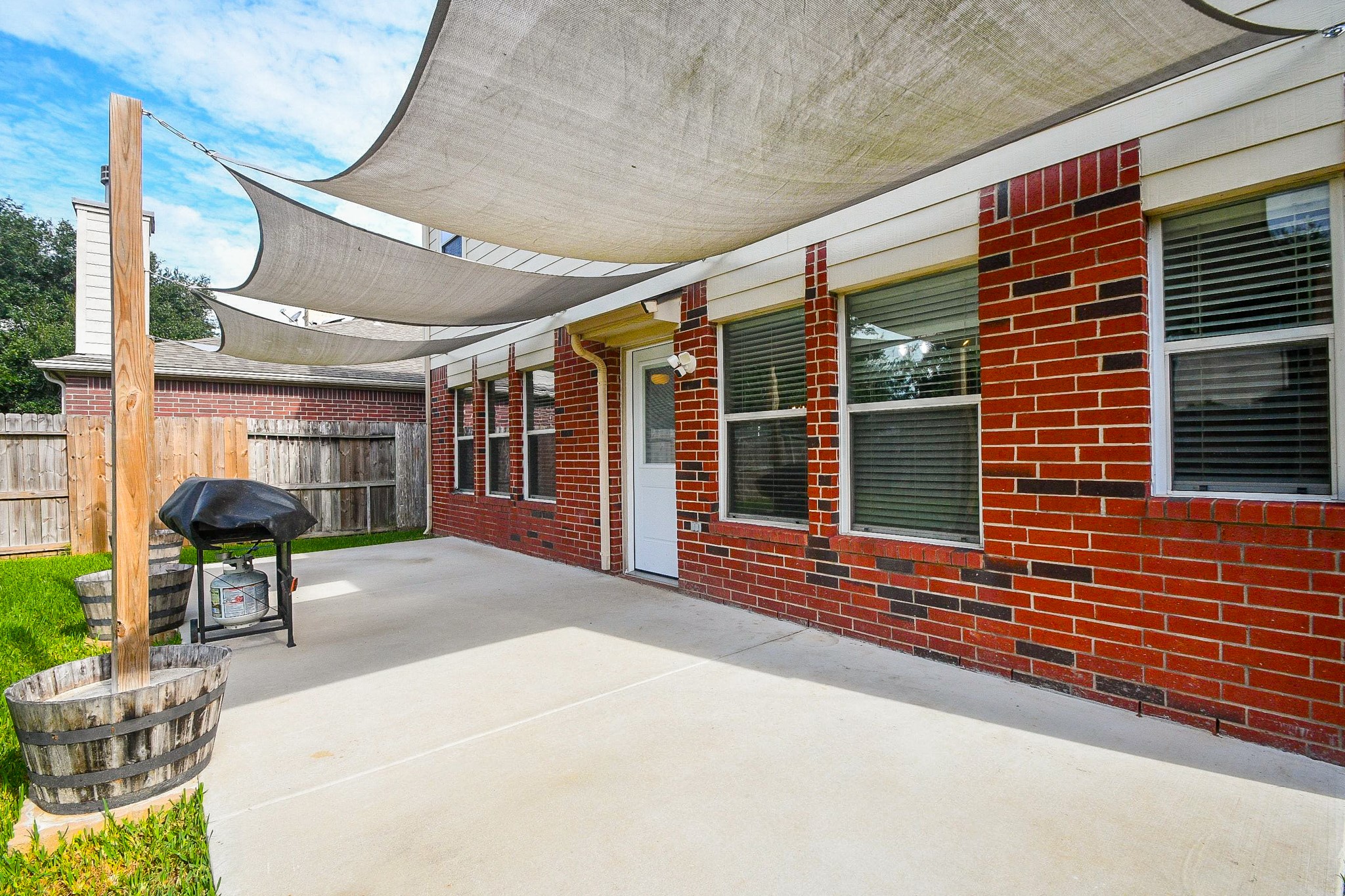 Spacious backyard patio with stylish shade sails, perfect for outdoor grilling and relaxation.