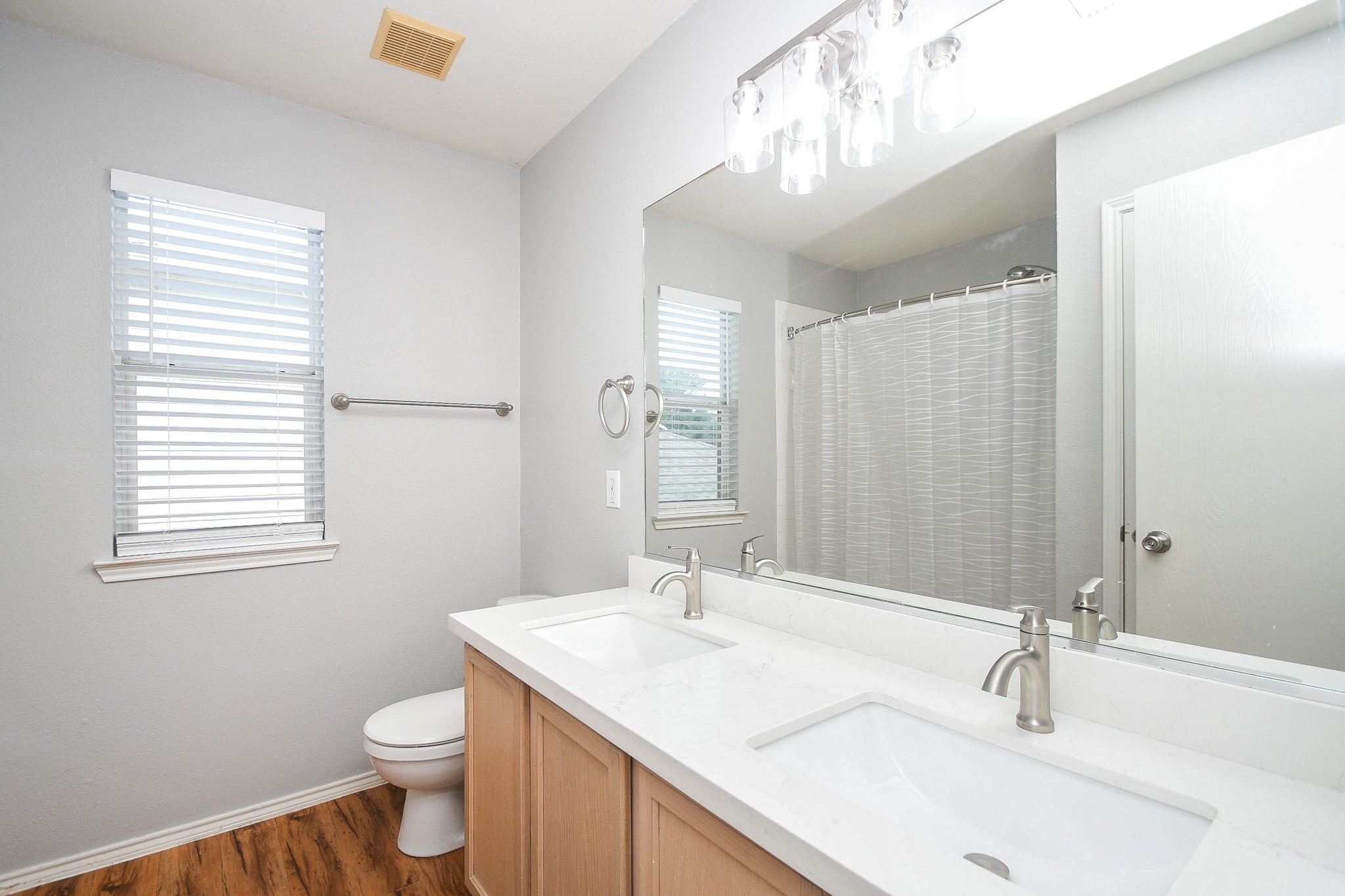 Bright and inviting bathroom featuring a double vanity with a sleek, modern design, complemented by a large mirror and contemporary light fixtures.
