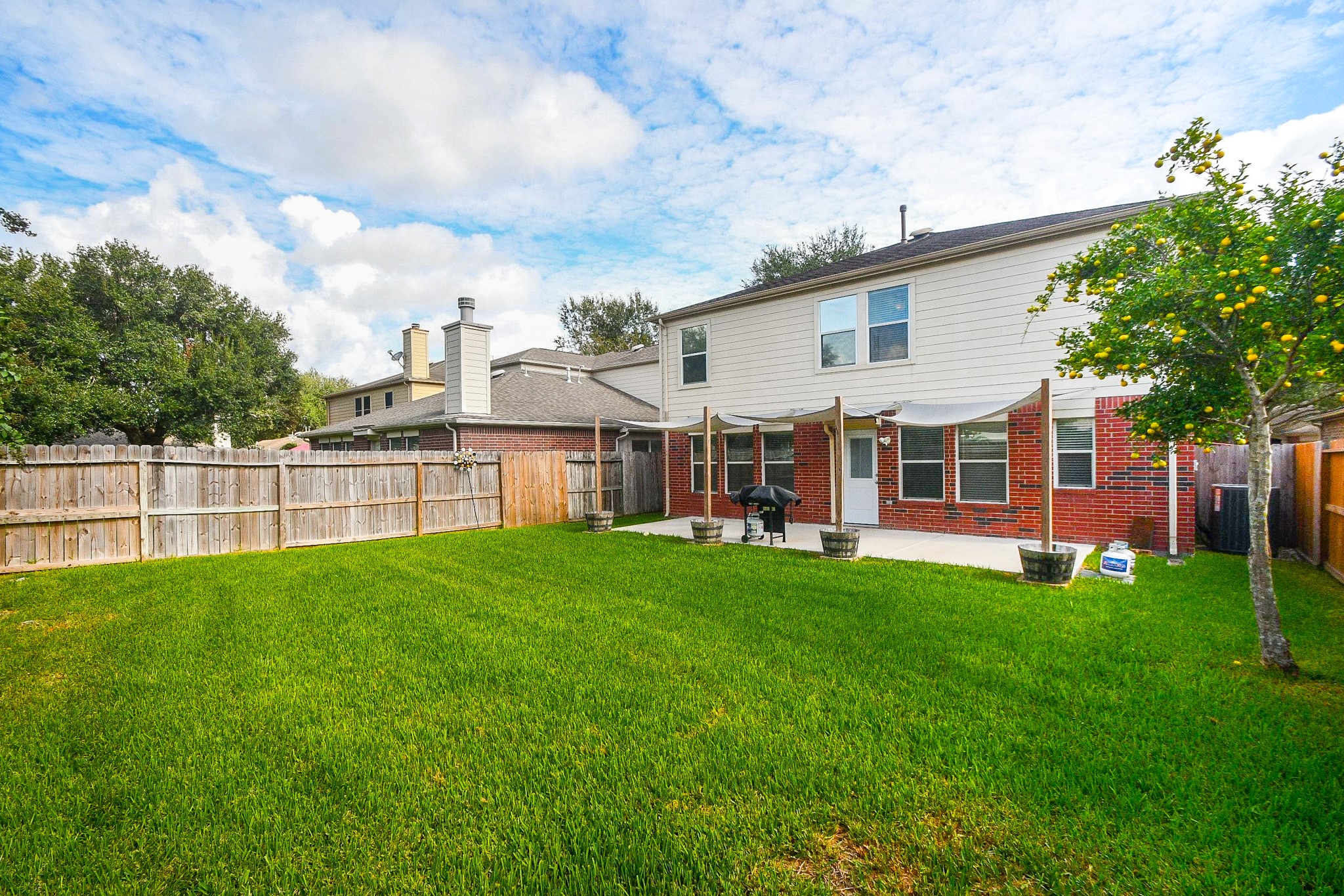 Spacious backyard with lush green lawn, perfect for outdoor activities, complemented by a charming patio area for relaxation and entertaining.