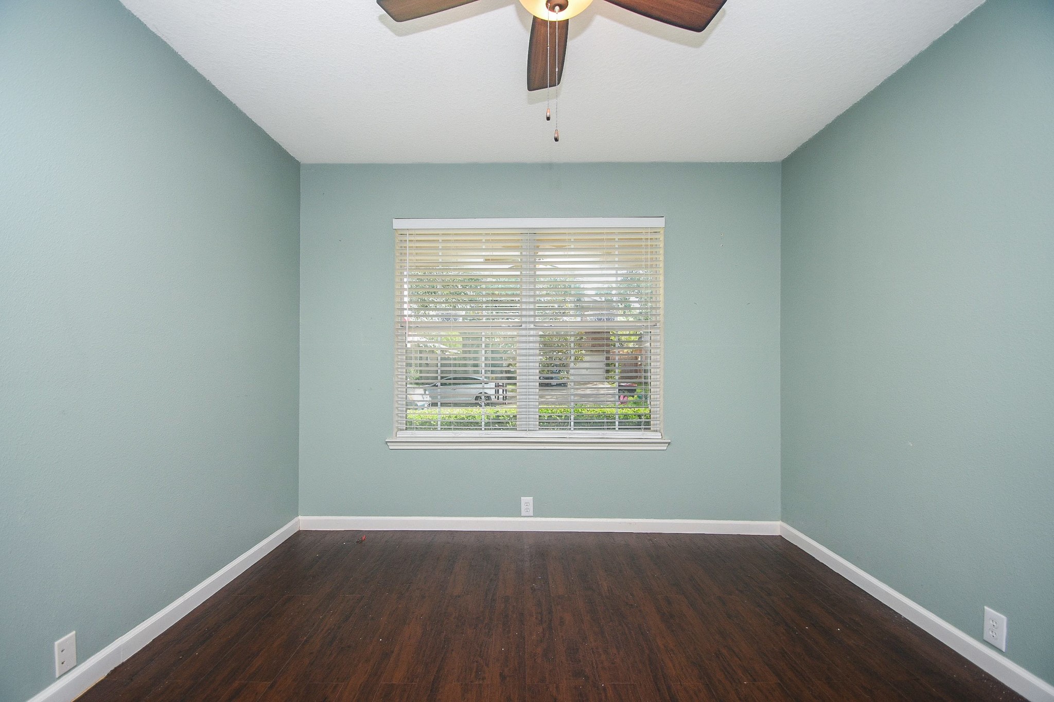 Soothing green wall paint and a large window inviting natural light, complemented by a ceiling fan for comfort. Soothing green wall paint and a large window inviting natural light, complemented by a ceiling fan for comfort.