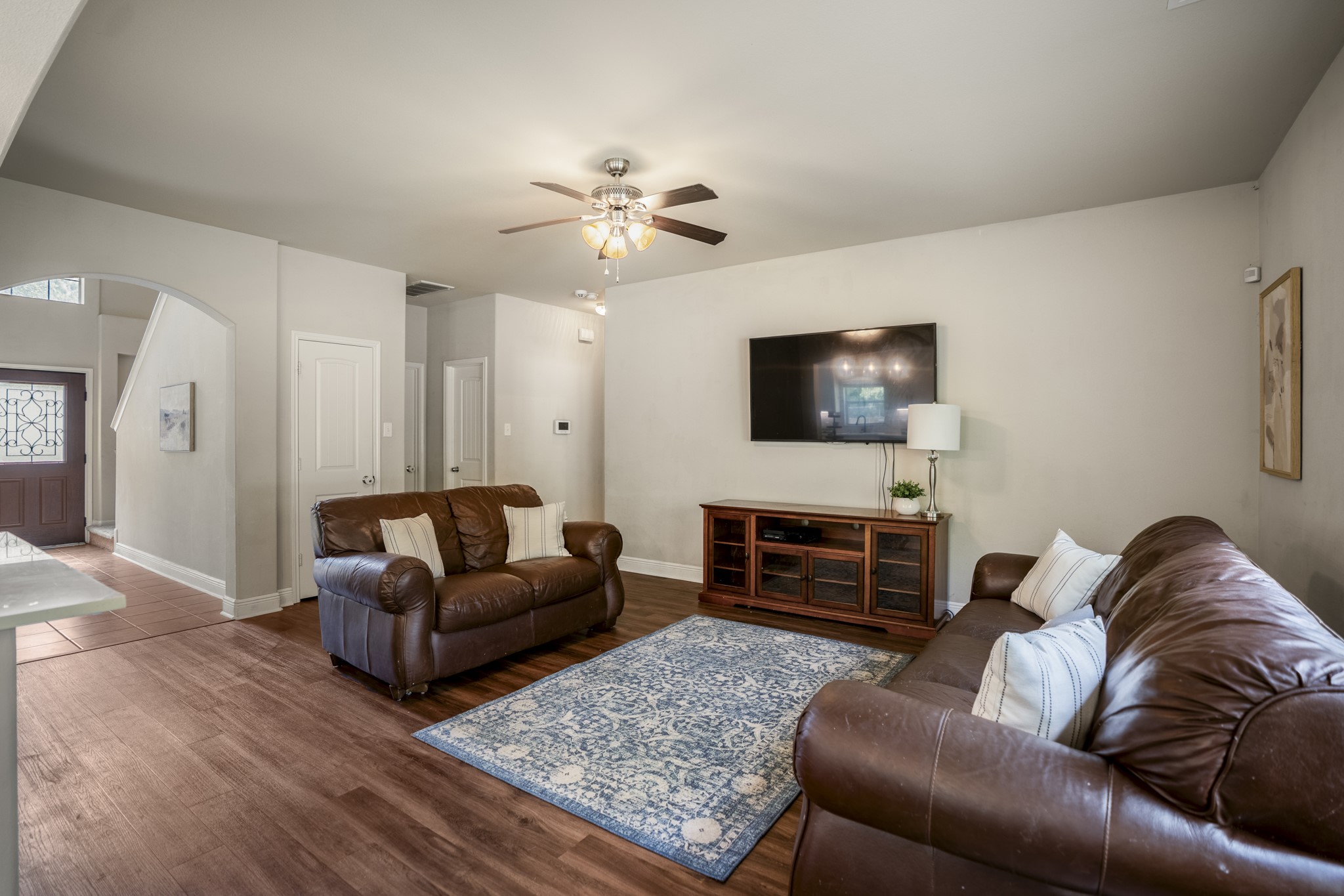 This angle shows the living room opening just beyond the kitchen and breakfast area, giving everyone a comfortable place to gather without feeling removed from whats happening nearby. Vinyl plank flooring continues through the space, while windows along the exterior wall pull in natural light and backyard views.
