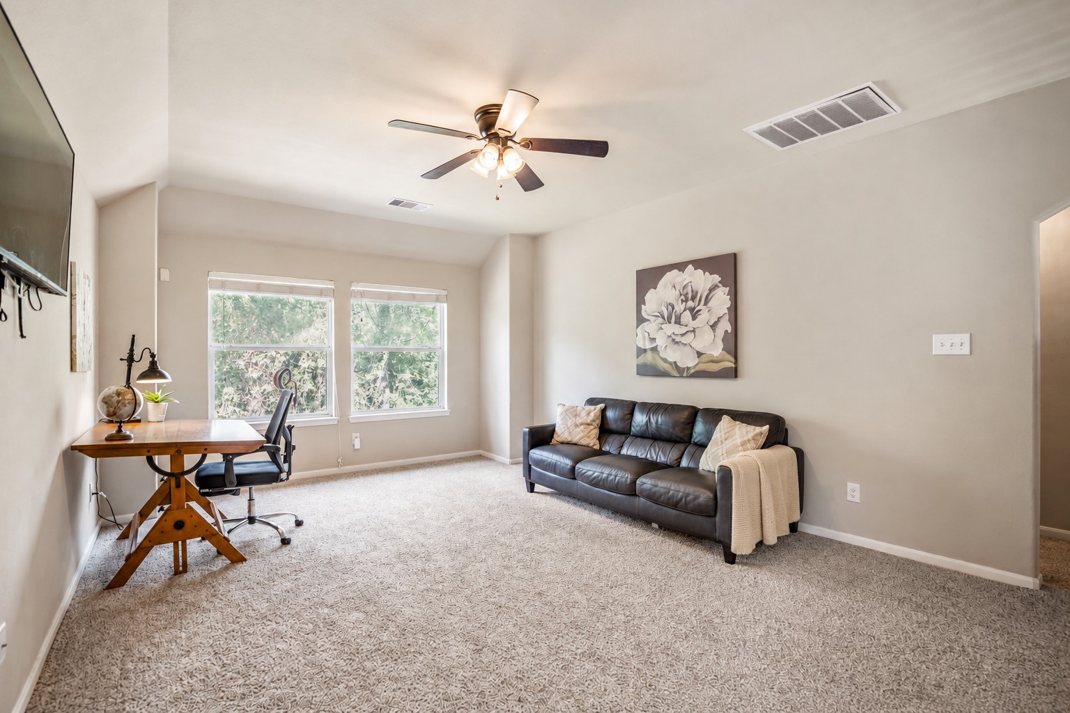 At the top of the stairs, the oversized gameroom opens up with plenty of room to spread out for movie nights, playtime, or a second hangout space. Natural light fills the room from the windows ahead, while the arched opening to the right leads to the upstairs full bath well come back to later.