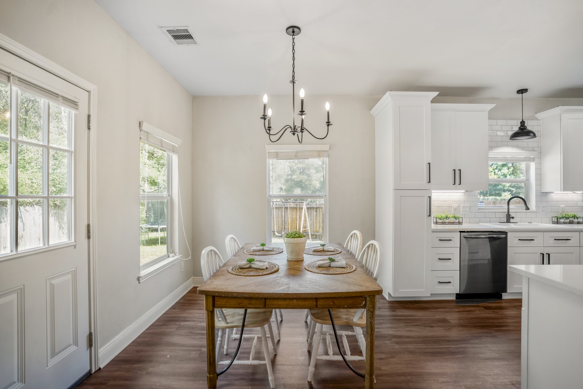 Just beyond the living room, the breakfast area sits between the kitchen and backyard, giving casual meals their own sunny spot. The door on the left leads outside, making it easy to carry dinner to the patio, step out with morning coffee, or keep an eye on whats happening in the yard.