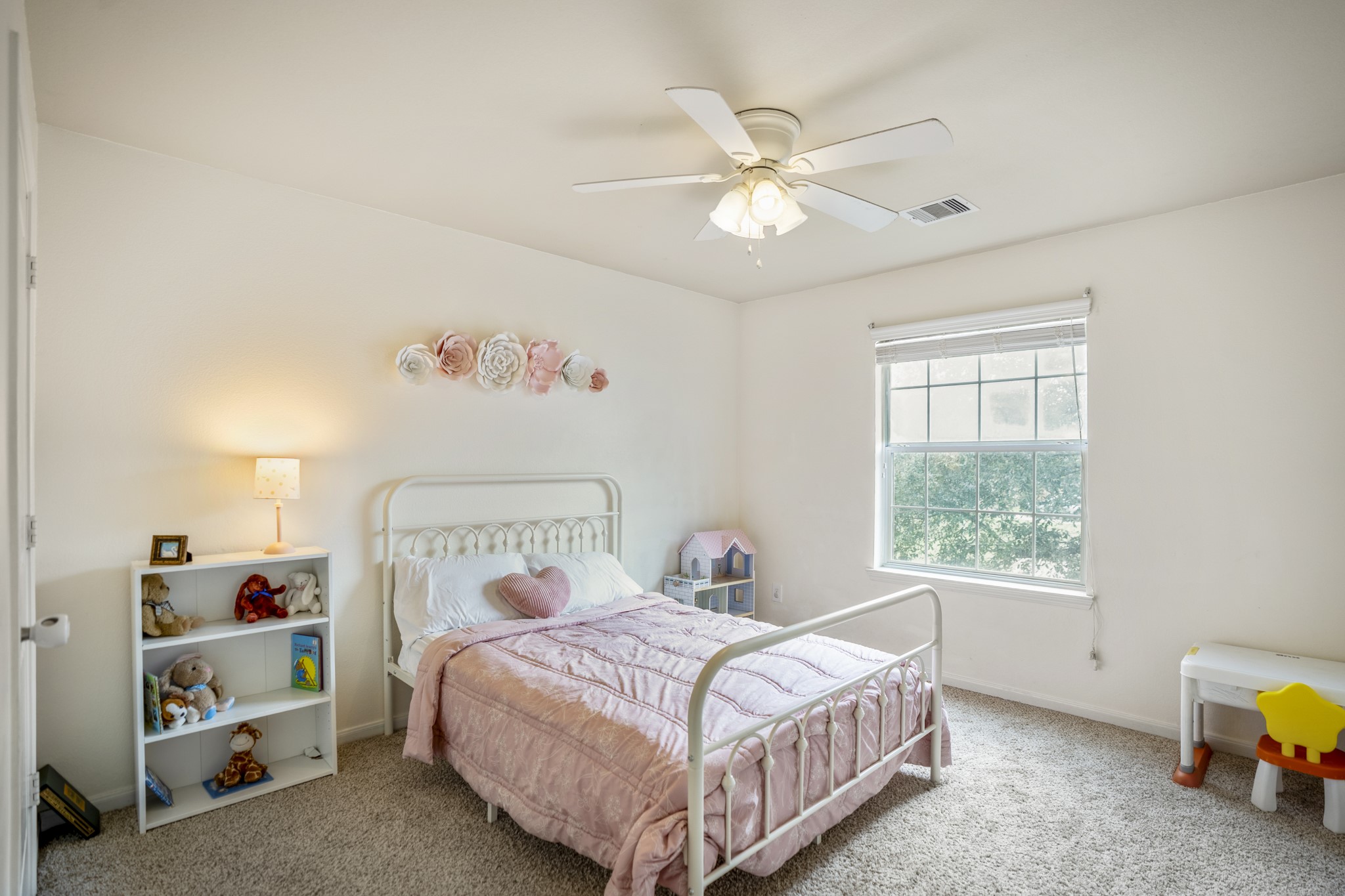 The third bedroom keeps things light and neutral with new carpet, a ceiling fan, and a window bringing in natural light.