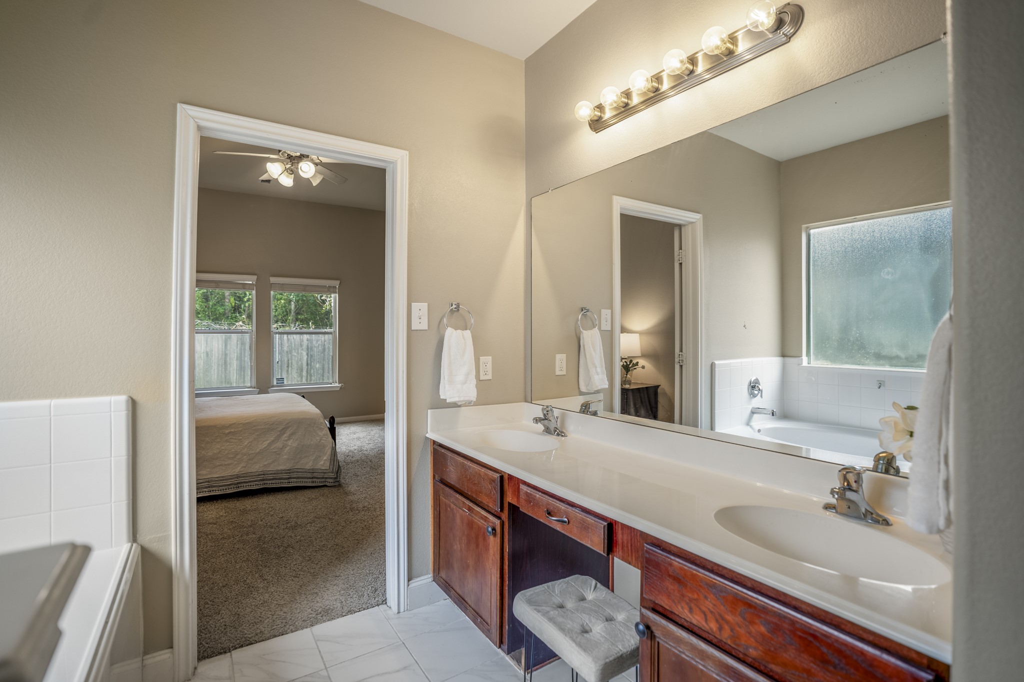 This closer look at the primary bath highlights the dual vanity with plenty of counter space, storage below, and a window bringing in natural light. The doorway ahead leads back into the primary bedroom, keeping the suite easy to navigate while giving the bath its own defined space.