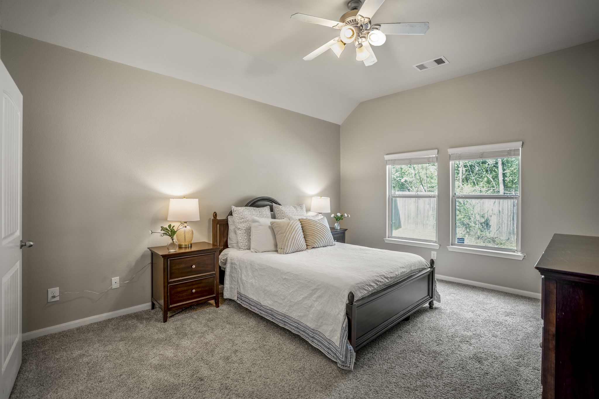 The downstairs primary bedroom offers a quieter place to unwind, with new carpet underfoot and a large window bringing in natural light and backyard views.