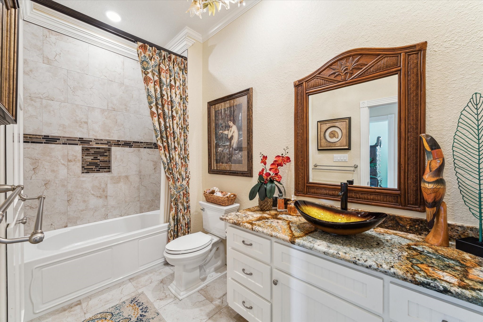 The updated guest bath provides a large vanity with vessel sink, updated tile floors & shower stalls, a Kohler tub with custom shower curtain, toilet with soft close lid & new plumbing fixtures. There is additional storage space in the linen closet.