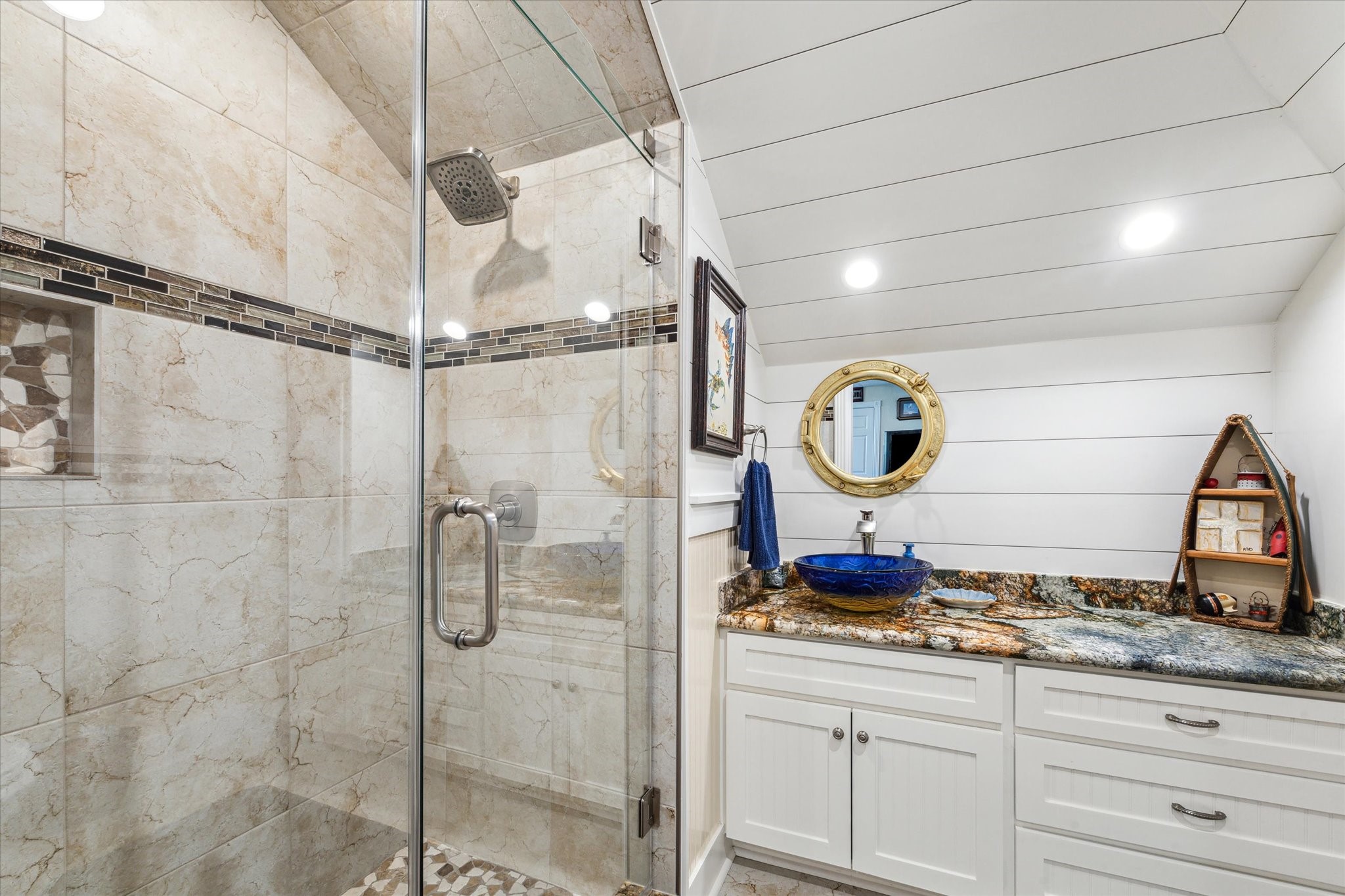 The coastal feel and details continue in the upstairs bathroom with the shiplap, custom walk-in shower, upgraded granite vanity with beautiful vessel sink.