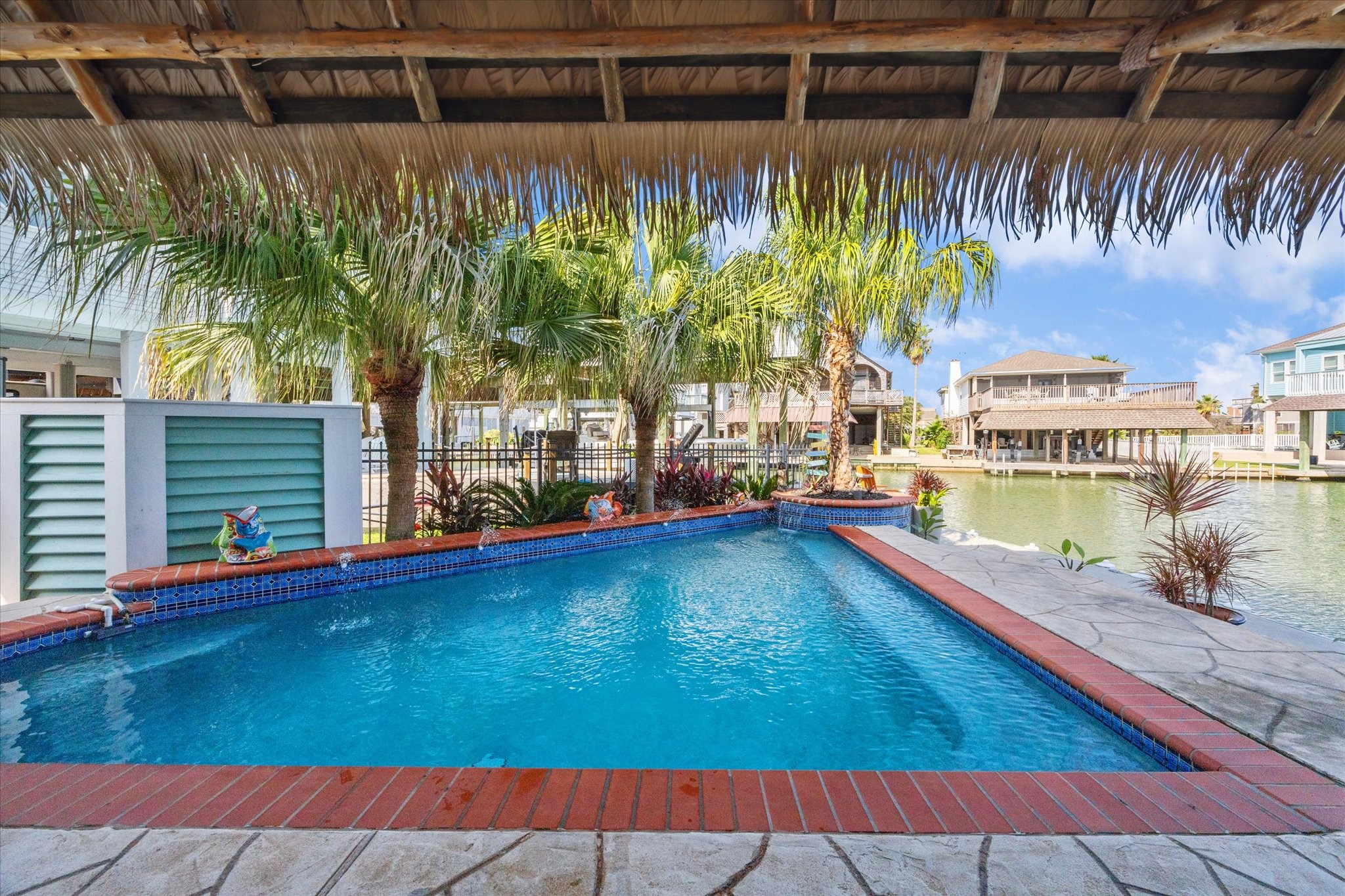 Welcome to your outdoor oasis with a heated pool overlooking the water, lushious landscaping, 118' of concrete bulkhead with bumper guards, 2 covered boat slips with lifts, tiki bar, synthetic palapa covering, 150 gallon bait well, stainless fish cleaning station with sink, ground level half bath, 4 garages and so much more!