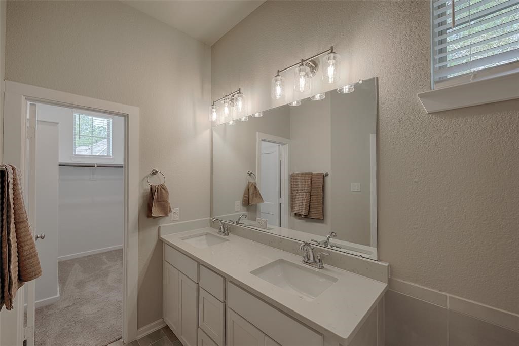 Primary bedroom has double sinks and a large walking in closet with builtin shelving and a window.