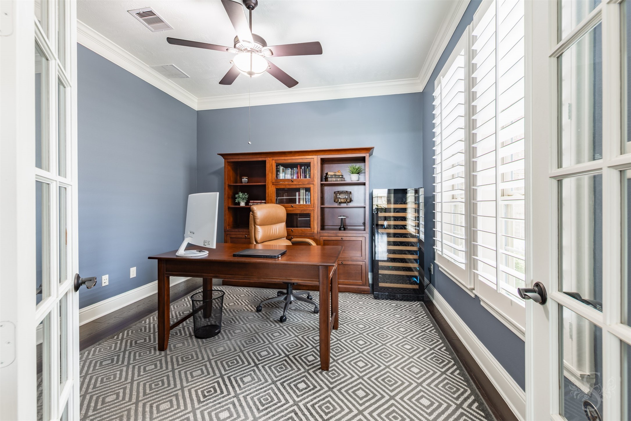 Framed by French doors, the private study pairs rich wood flooring with soft blue walls and crisp crown molding. Expansive windows with plantation shutters create an inviting setting for working from home or enjoying a quiet read. Framed by French doors, the private study pairs rich wood flooring with soft blue walls and crisp crown molding. Expansive windows with plantation shutters create an inviting setting for working from home or enjoying a quiet read.