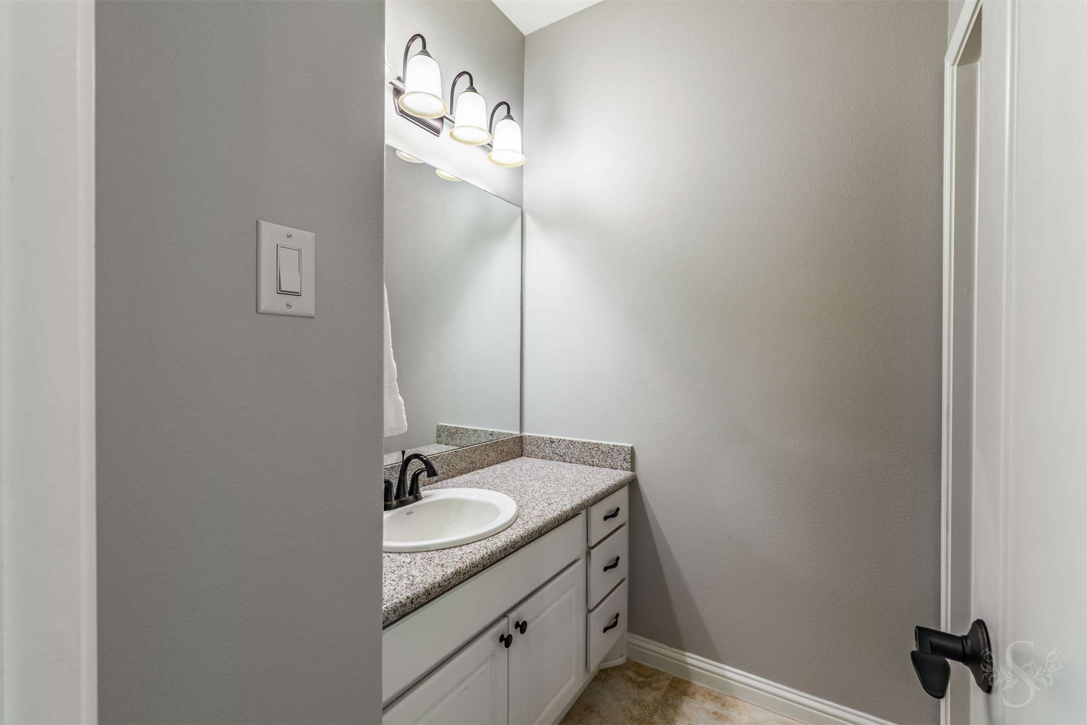 A granite-topped vanity with crisp white cabinetry offers generous counter space for daily routines.