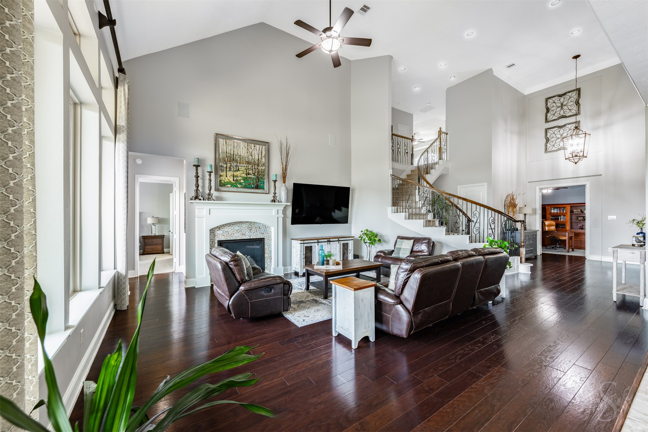An impressive vaulted ceiling and rich wood flooring give the family room a luxurious sense of scale. Gather around the elegant fireplace or entertain friends in this expansive space, with the curved staircase creating a striking backdrop. An impressive vaulted ceiling and rich wood flooring give the family room a luxurious sense of scale. Gather around the elegant fireplace or entertain friends in this expansive space, with the curved staircase creating a striking backdrop.