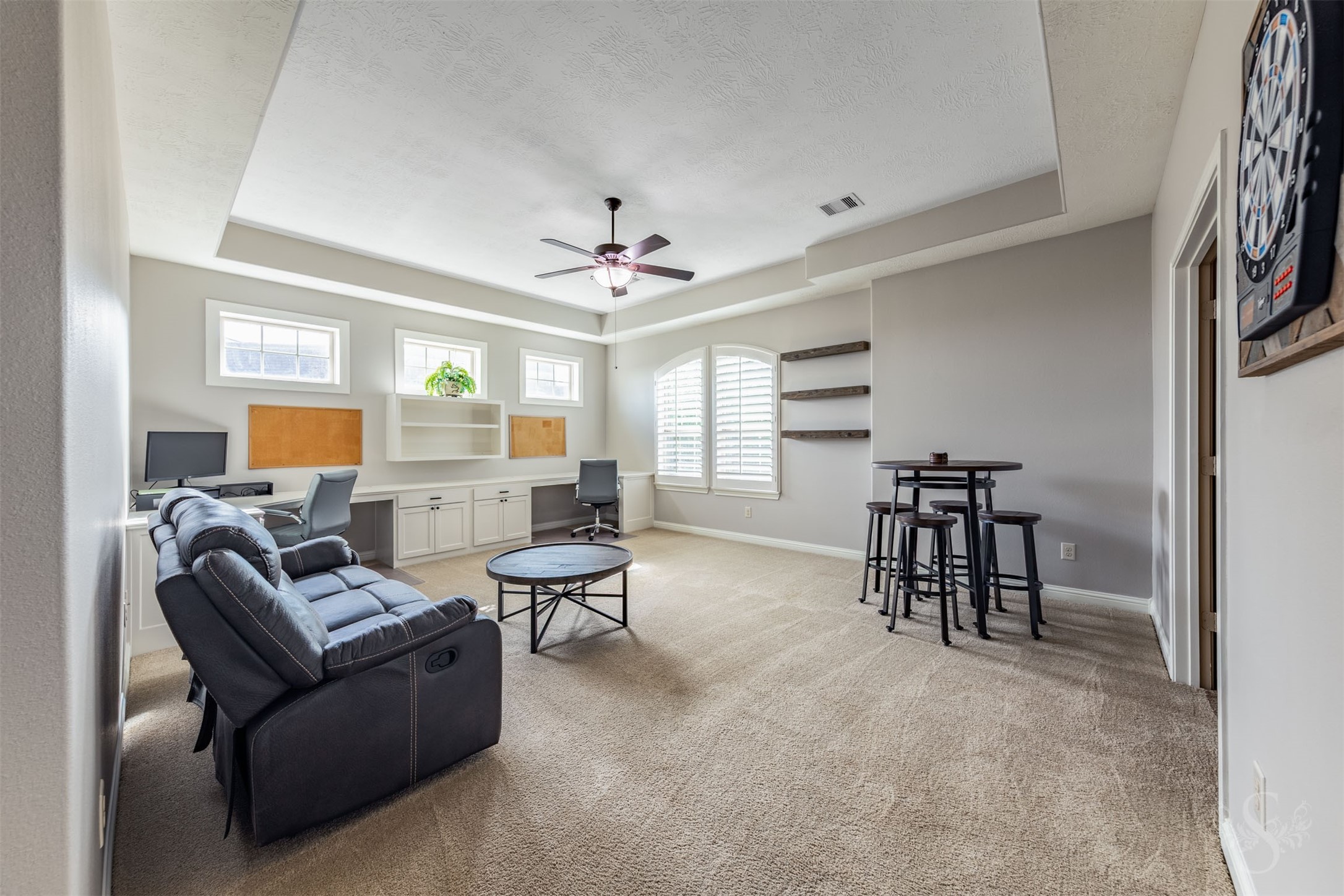 A striking tray ceiling and arched window with plantation shutters give the spacious upstairs game room distinctive character. Built-in desks, cabinetry and shelving create a versatile space for homework, creative projects and family fun.