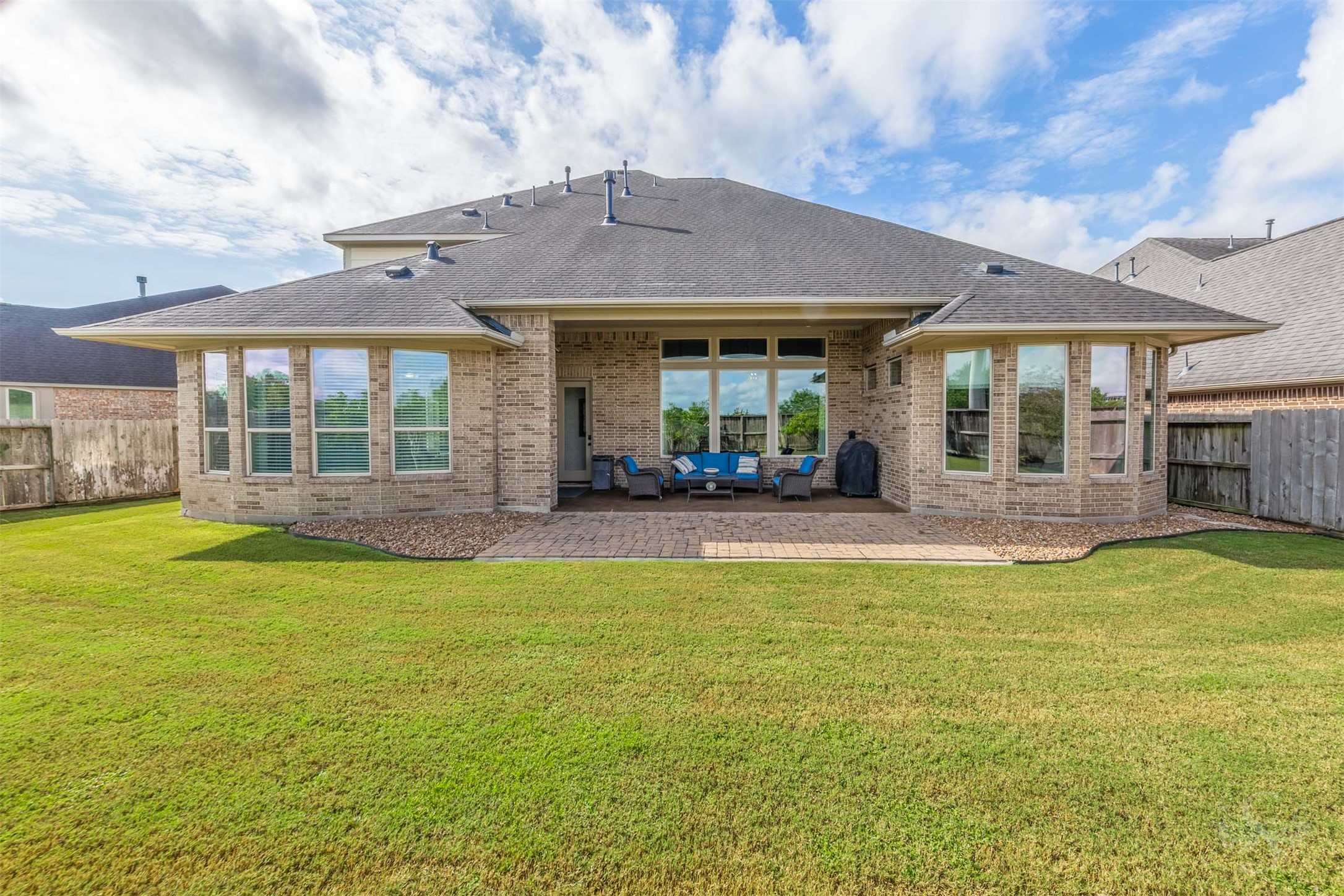 The homes impressive rear elevation pairs graceful bay windows with a covered outdoor retreat overlooking the backyard. Gather beneath the patios shelter or enjoy dinner on the extended paver terrace, with plenty of green space beyond.
