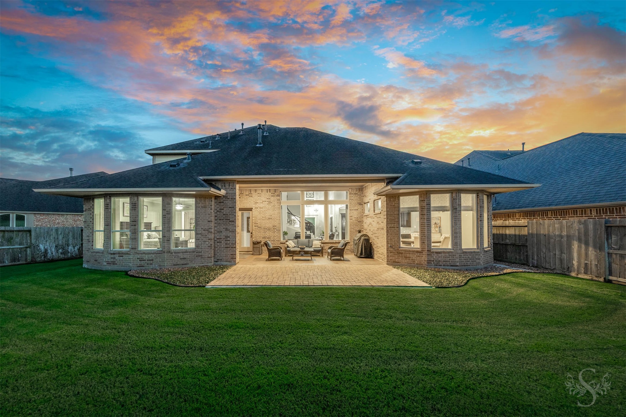 The homes impressive rear elevation pairs graceful bay windows with a covered outdoor retreat overlooking the backyard. Gather beneath the patios shelter or enjoy dinner on the extended paver terrace, with plenty of green space beyond.