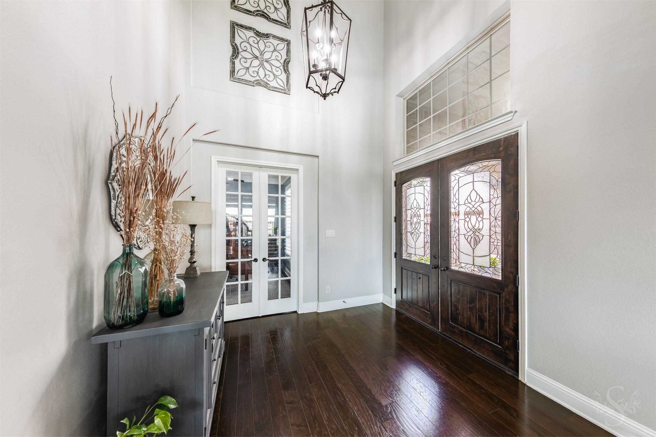Beautiful double doors with decorative glass open to an impressive entry featuring rich wood flooring and a striking lantern chandelier. A large transom window highlights the entrys impressive height, while French doors introduce the private study. Beautiful double doors with decorative glass open to an impressive entry featuring rich wood flooring and a striking lantern chandelier. A large transom window highlights the entrys impressive height, while French doors introduce the private study.