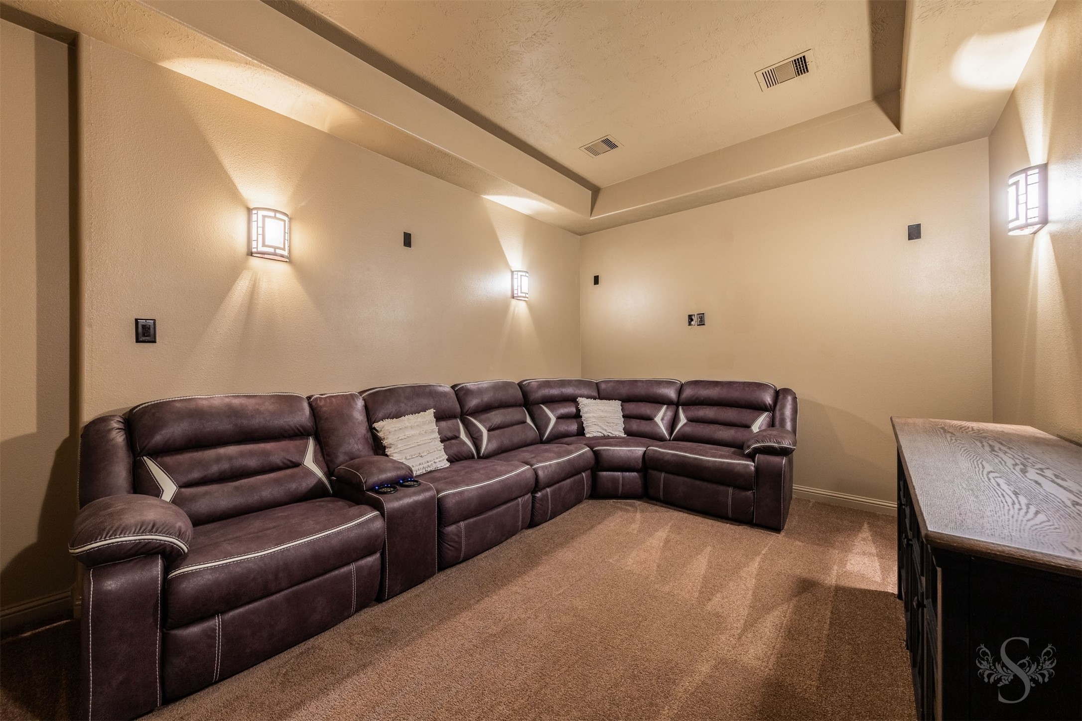 Enjoy a cinematic escape in the private media room, featuring a dramatic tray ceiling and softly glowing wall sconces. Plush carpeting and a windowless setting make this inviting retreat perfect for movie nights and watching the big game.