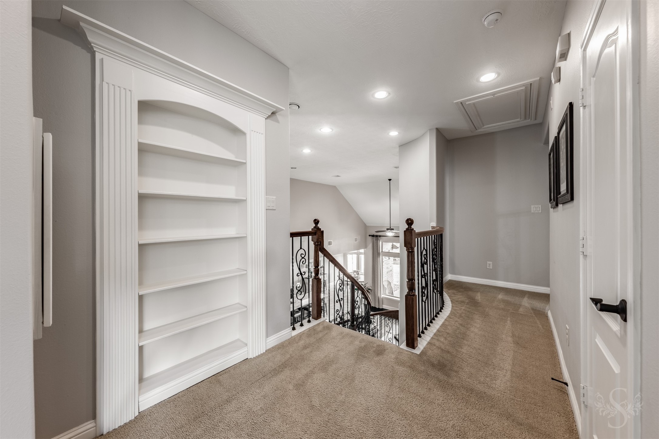 A beautifully trimmed built-in bookcase adds character to the upstairs landing, offering space to display favorite books and treasured collections. Curved iron railing overlooks the family room, extending the homes elegant architectural details to the second floor.