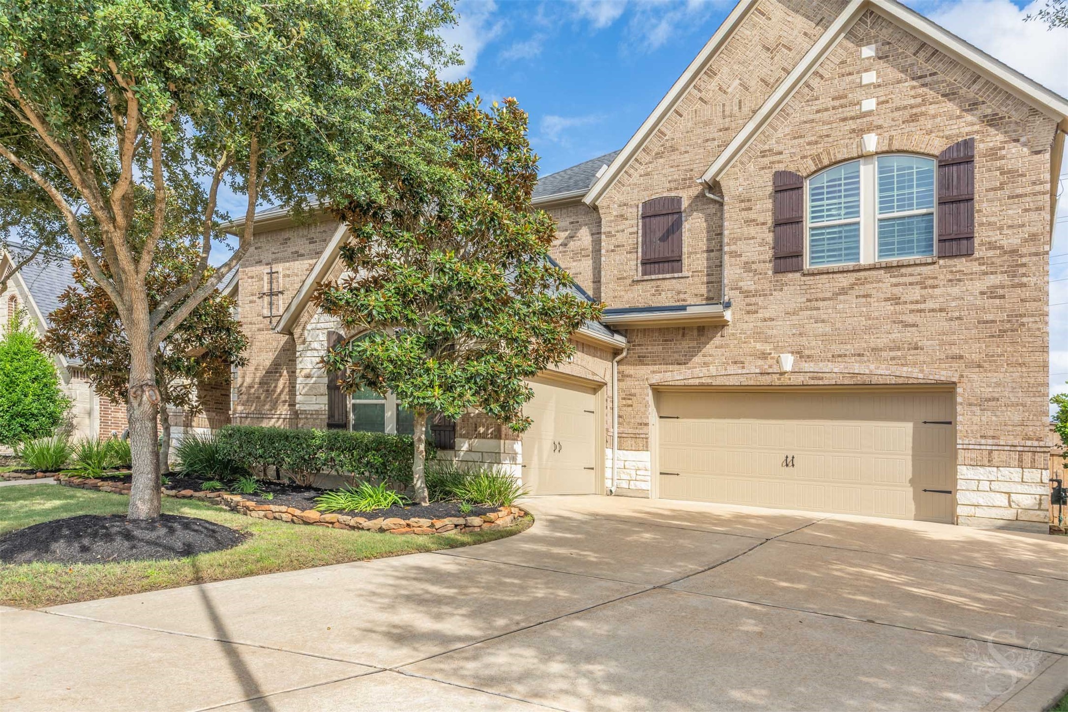 A spacious driveway leads to the 3 car garage, offering generous parking for everyday convenience and welcoming visitors. Rich brick textures, decorative shutters and stone-bordered planting beds carry the homes classic style across the exterior.