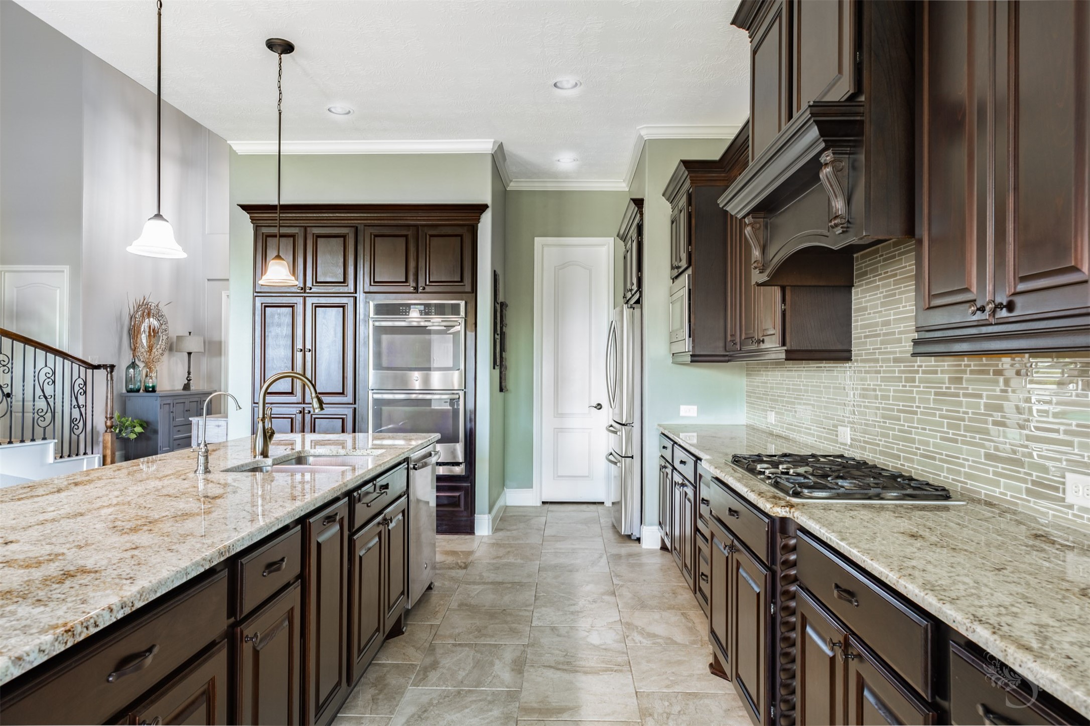 Richly stained cabinetry, expansive granite counters and a decorative wood vent hood give this kitchen timeless elegance. Stainless steel double ovens, a gas cooktop and an island with abundant storage offer a beautiful setting for preparing everything from casual dinners to meals for a crowd.