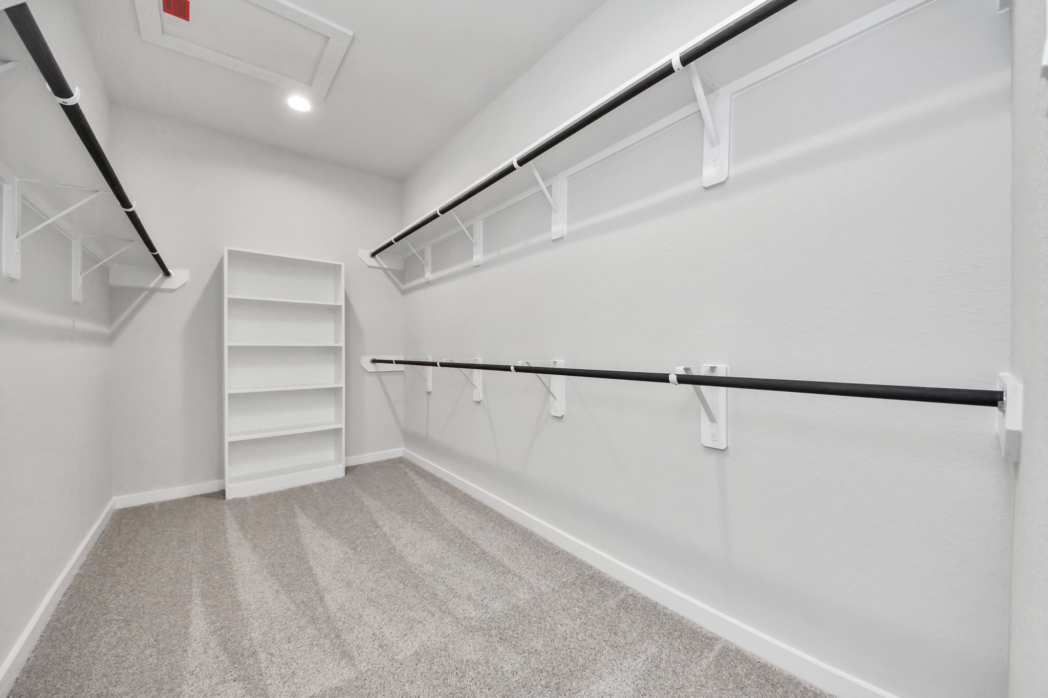 Walk-in closet that epitomizes luxury and practicality. This generously sized space features built-in shelving, offering abundant room for impeccable organization. High ceilings and recessed lighting create a bright and welcoming ambiance. Sample photo of completed home with similar floor plan. Actual colors and selections may vary.