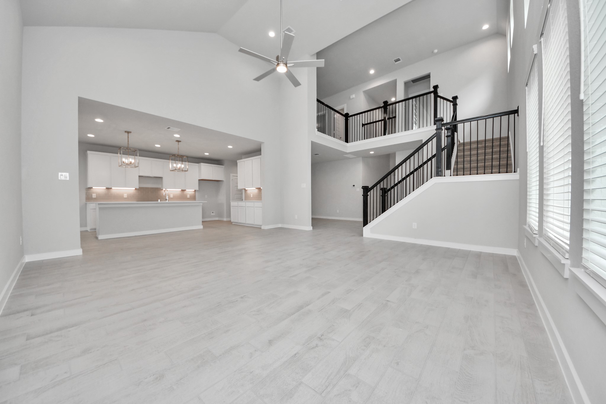 Welcome family and guests to your charming living room! With its high ceilings, recessed lighting, ceiling fan, custom paint, beautiful flooring, and large windows that let in abundant natural light, this room is perfect for gatherings. Sample photo of completed home with similar floor plan. Actual colors and selections may vary.