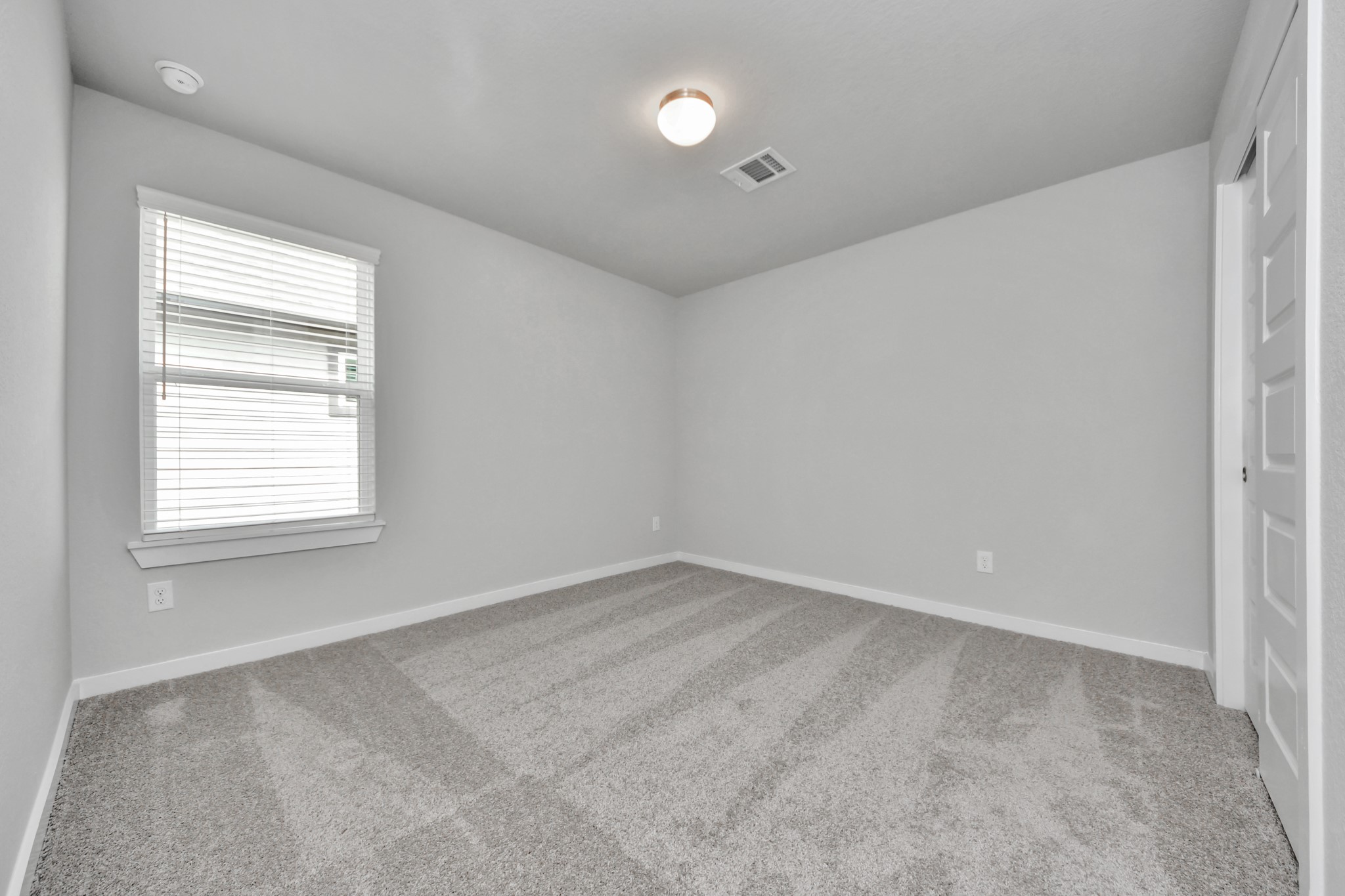 Secondary bedroom features plush carpeting, large windows that let in plenty of natural light, bright paint, and spacious closets. Sample photo of completed home with similar floor plan. Actual colors and selections may vary.