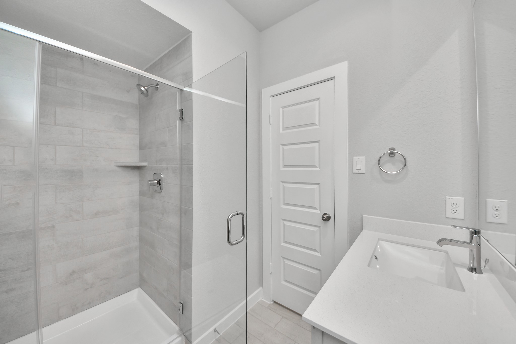 Secondary bath features tile flooring, walk-in shower with tile surround, light stained wood cabinets, beautiful light countertop. Sample photo of completed home with similar floor plan. Actual colors and selections may vary.