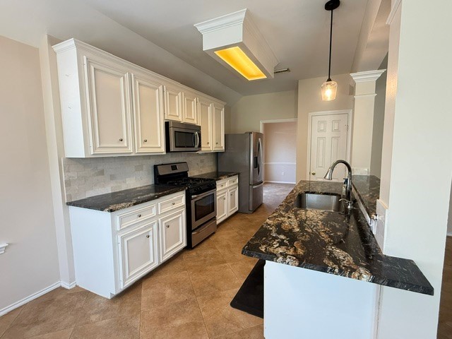 Elegant kitchen featuring sleek granite countertops, stainless steel appliances, and classic white cabinetry, complemented by a chic pendant light fixture.