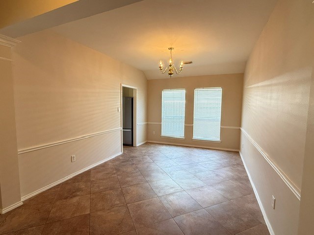 Spacious dining area or could be open home office with elegant chandelier, large windows for natural light, and stylish tile flooring.