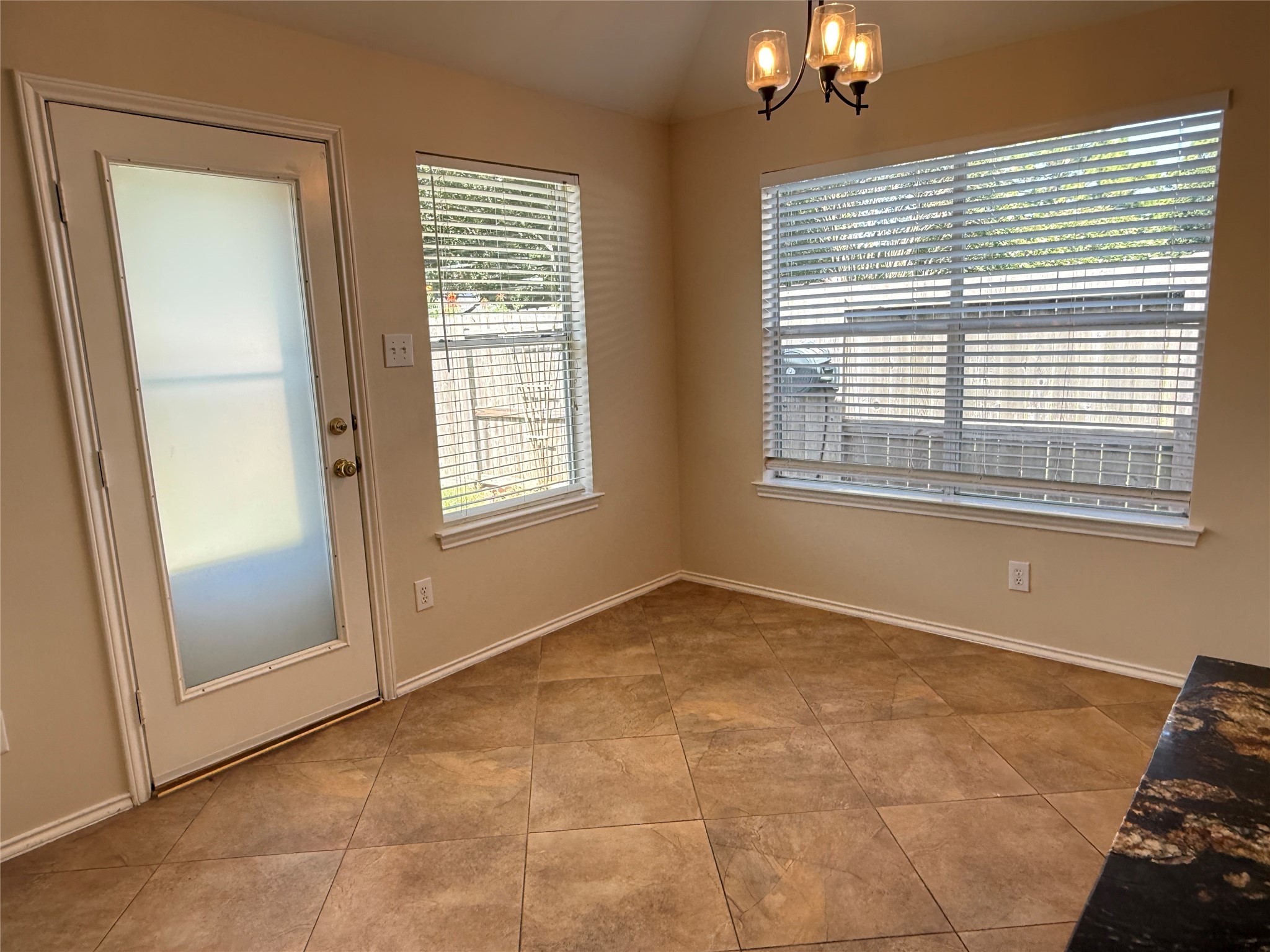 Bright and inviting breakfast nook with tile flooring, large windows, and a door leading to the backyard, perfect for morning coffee.