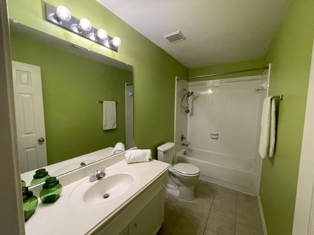 Guest bathroom featuring a sleek vanity with sink, a large mirror with modern lighting, and a spacious shower-tub combo, all enhanced by vibrant green walls.