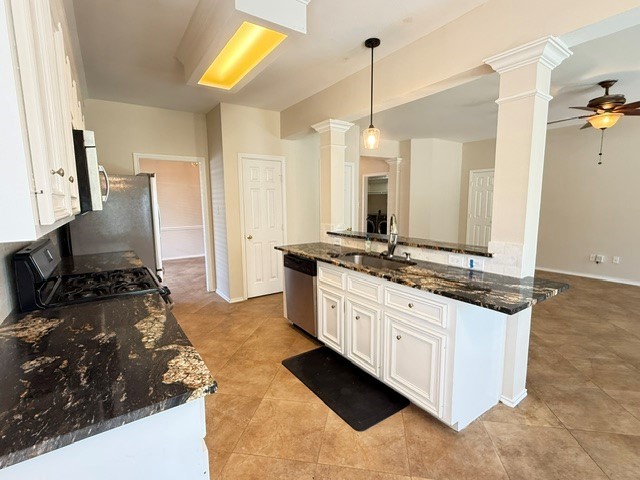 Spacious kitchen featuring elegant granite countertops, modern stainless steel appliances, and a convenient breakfast bar, seamlessly flowing into an open living area with stylish ceiling fan accents.
