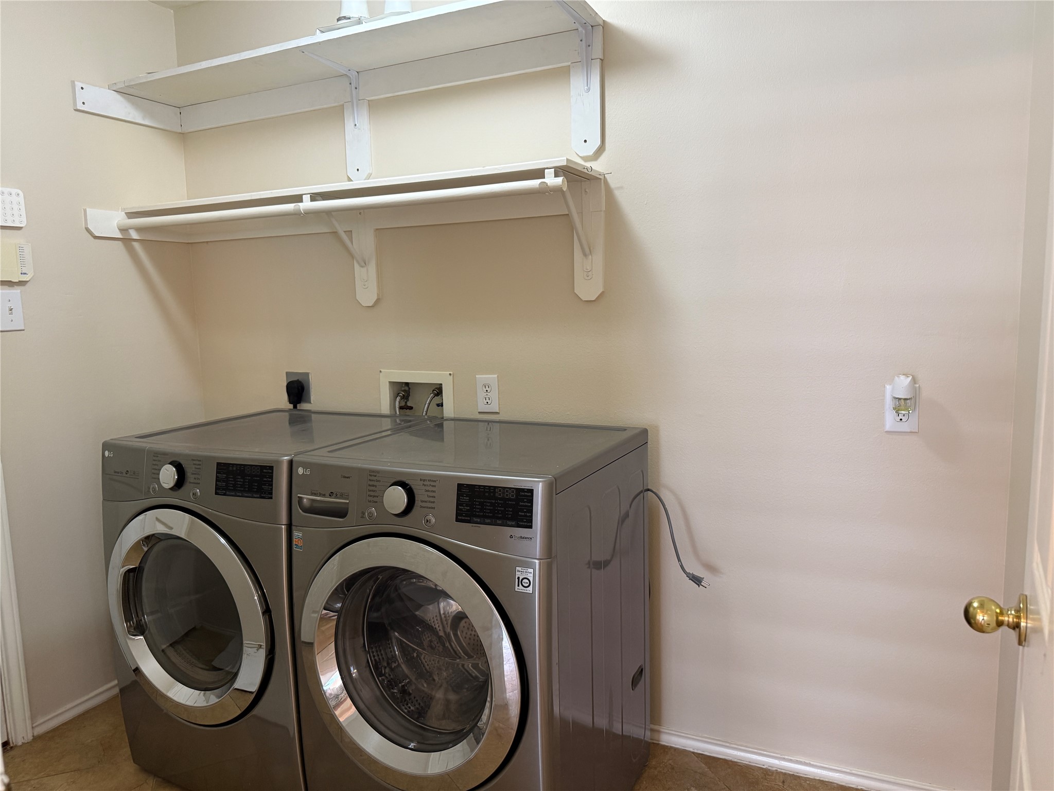 Modern laundry room featuring sleek stainless steel washer and dryer units, complemented by ample shelving for storage and organization.