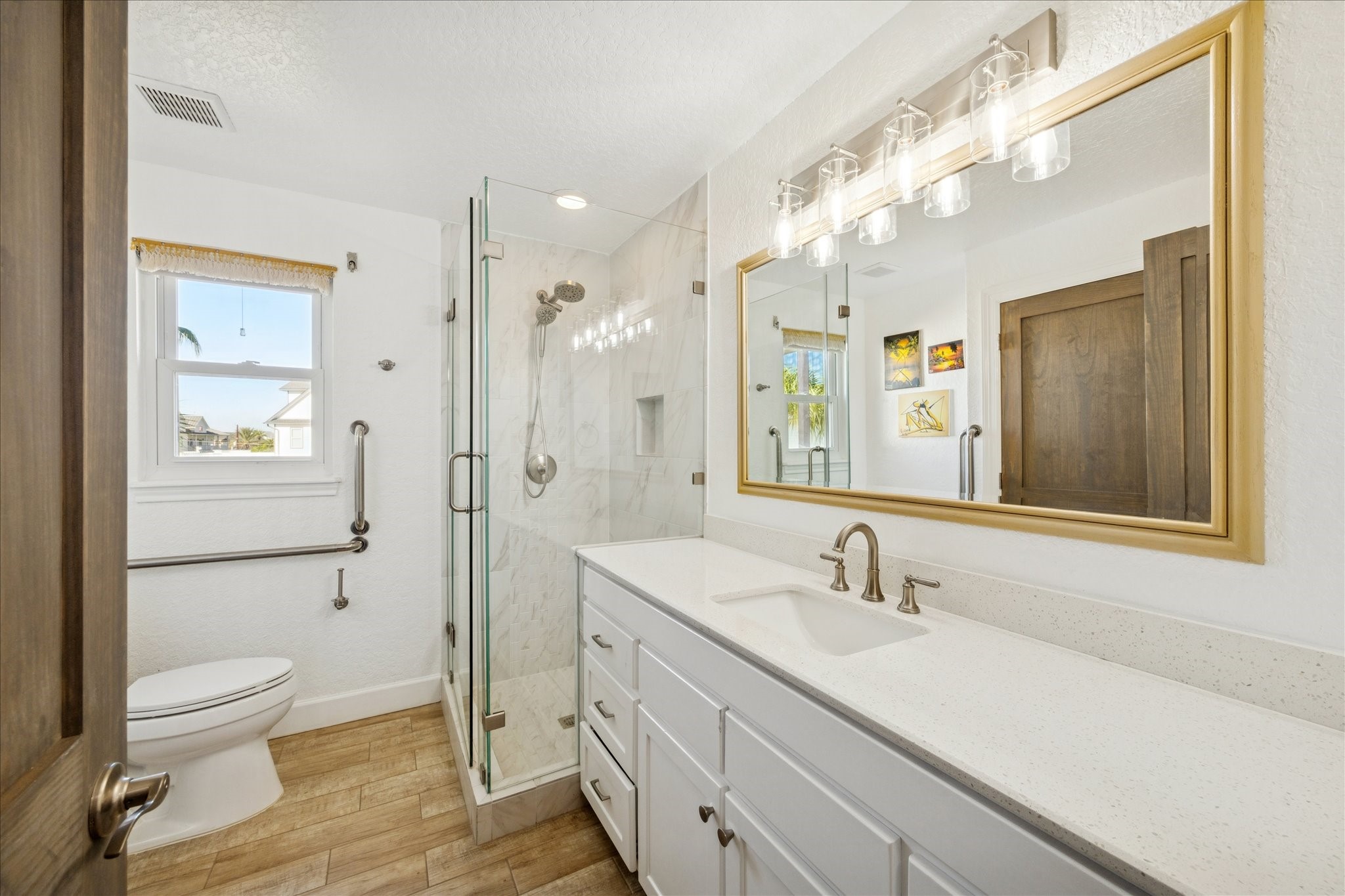 This beautifully updated first-floor bath features a long vanity, extra counter space and a glass-enclosed shower, creating a fresh, modern setting for family and guests.