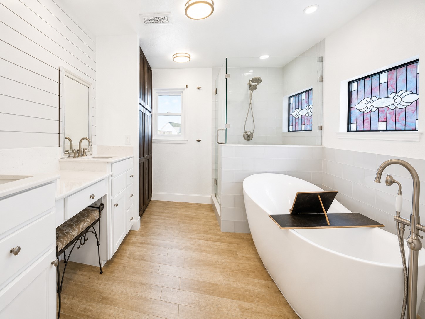 Step into your spa-like primary bath, beautifully updated and designed to easily accommodate two. Individual vanities set against a character-rich shiplap wall, a soaking tub, glass-enclosed shower, dedicated makeup vanity and custom floor-to-ceiling linen cabinet bring function and storage to the room.