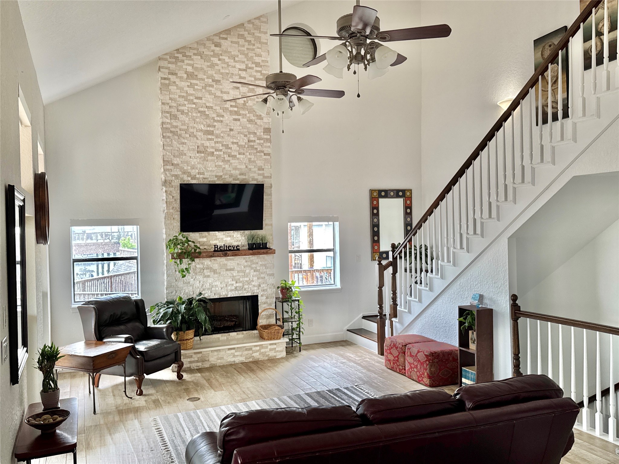 An open, expansive living area showcases the home's dramatic scale, anchored by a stone floor-to-ceiling wood-burning fireplace.