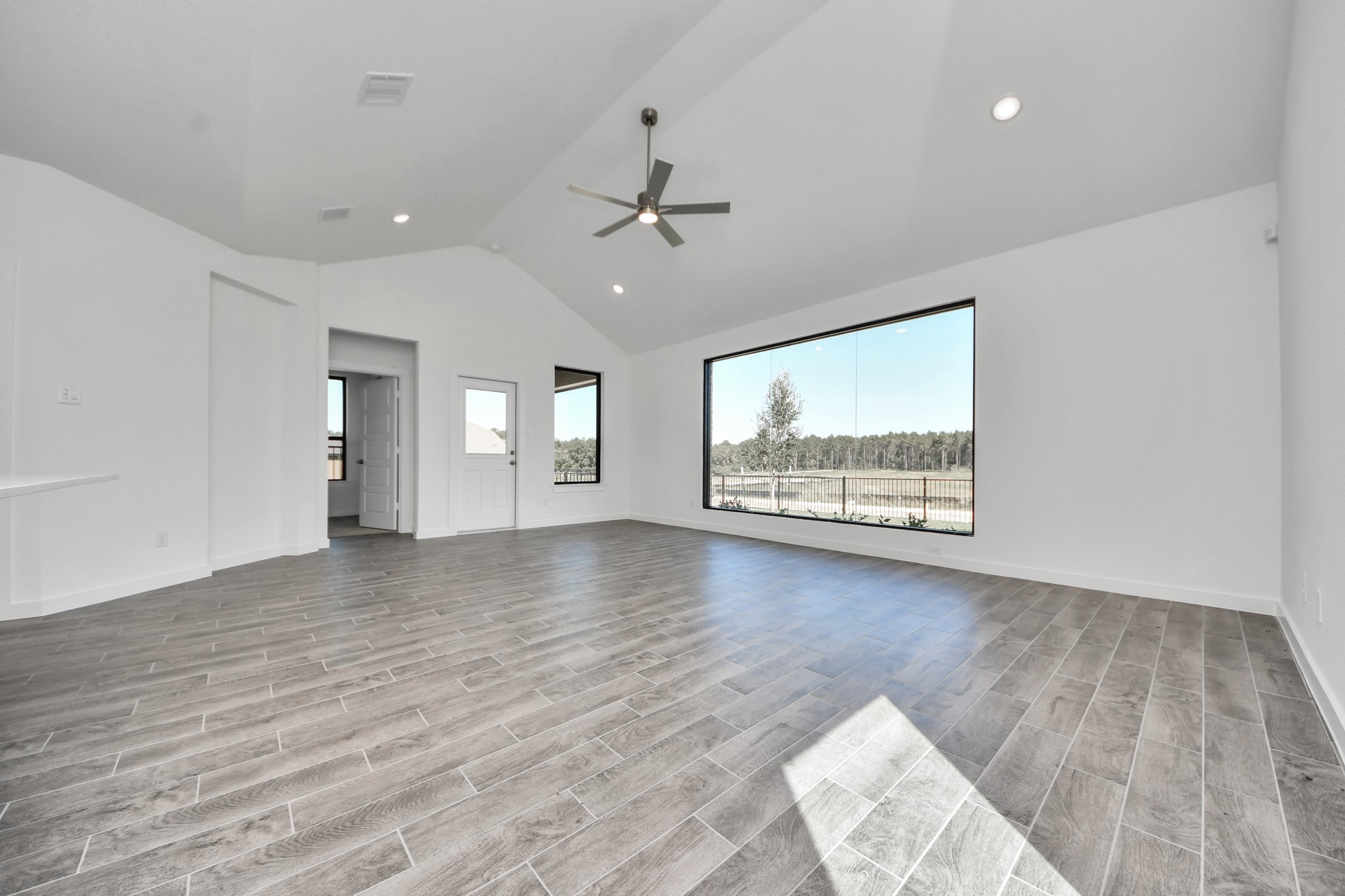 Welcome family and guests to your charming living room! With its high ceilings, recessed lighting, ceiling fan, custom paint, beautiful flooring, and large windows that let in abundant natural light, this room is perfect for gatherings. Sample photo of completed home with similar floor plan. Actual colors and selections may vary.