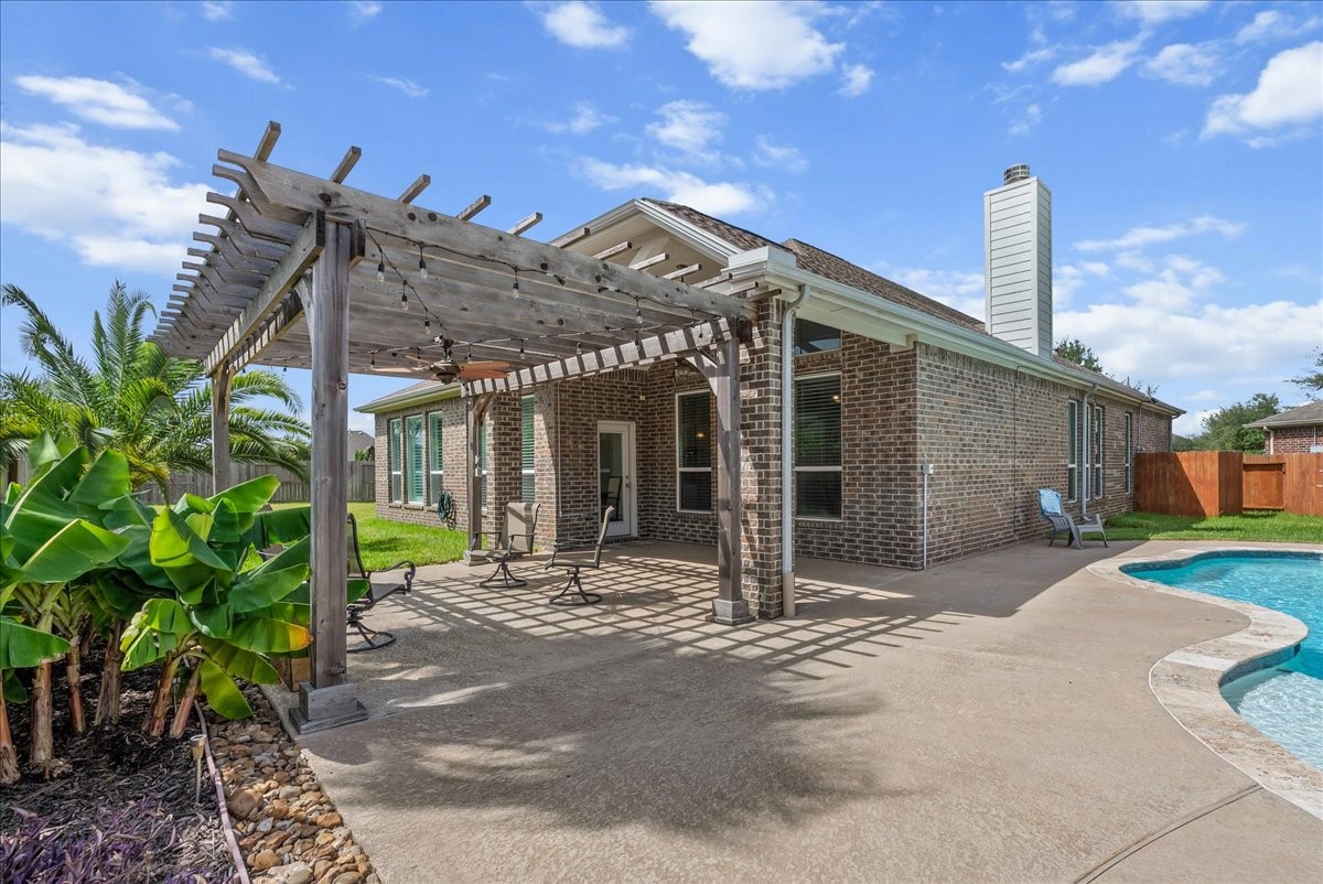 Experience outdoor living with a spacious patio featuring a charming pergola, overlooking a sparkling pool and lush greenery.  So many possibilities!