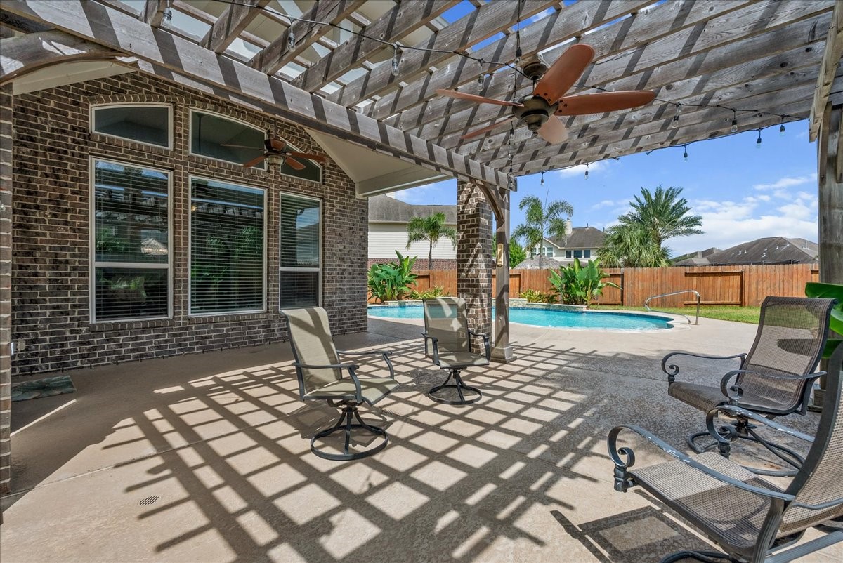 Relax in a spacious backyard oasis featuring a covered patio with ceiling fans, perfect for entertaining, overlooking a sparkling pool and lush landscaping. Relax in a spacious backyard oasis featuring a covered patio with ceiling fans, perfect for entertaining, overlooking a sparkling pool and lush landscaping.