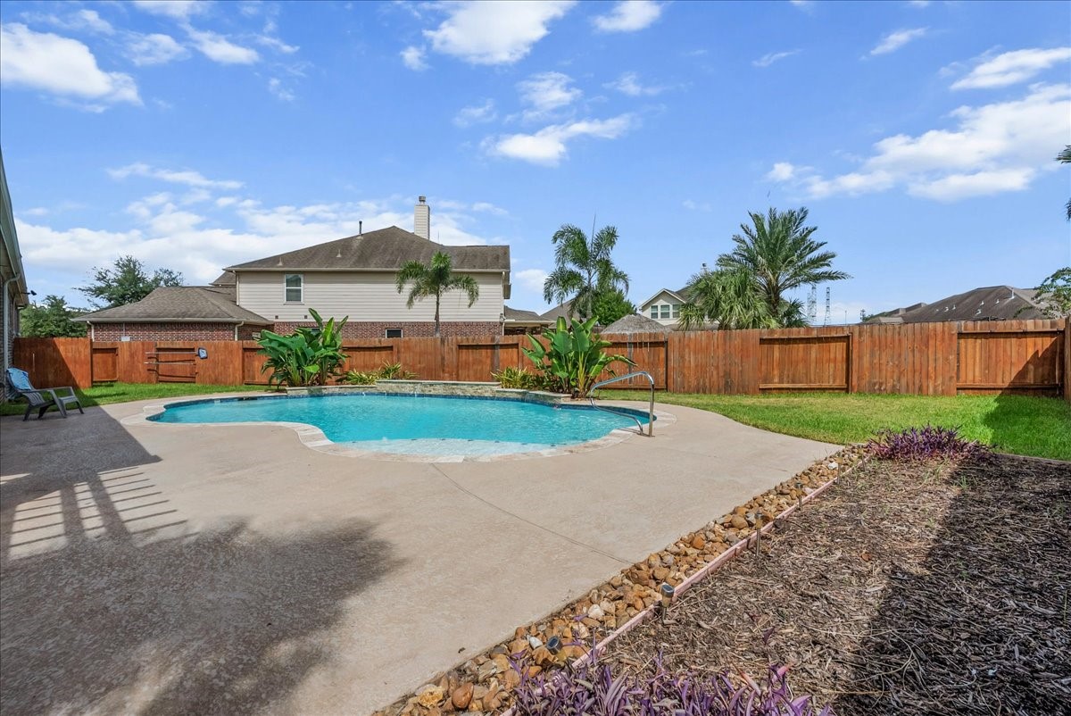 A spacious backyard oasis featuring a sparkling pool surrounded by a well-maintained deck and privacy fencing, perfect for relaxation and entertaining.