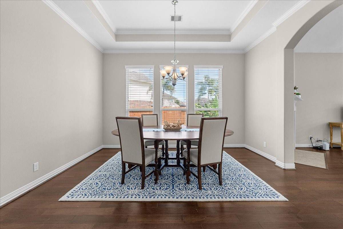 One more photo of the spacious dining room with a tray ceiling, featuring a stylish chandelier and large windows that offer plenty of natural light, complemented by classic engineered wood floors One more photo of the spacious dining room with a tray ceiling, featuring a stylish chandelier and large windows that offer plenty of natural light, complemented by classic engineered wood floors