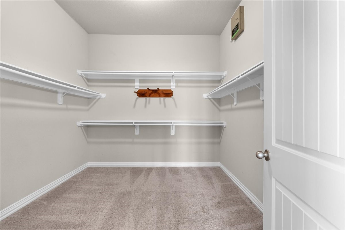 Spacious walk-in closet with ample shelving for organized storage and plush carpeting for a cozy feel.
The little rack on the back wall will hold some of your favorite hats.