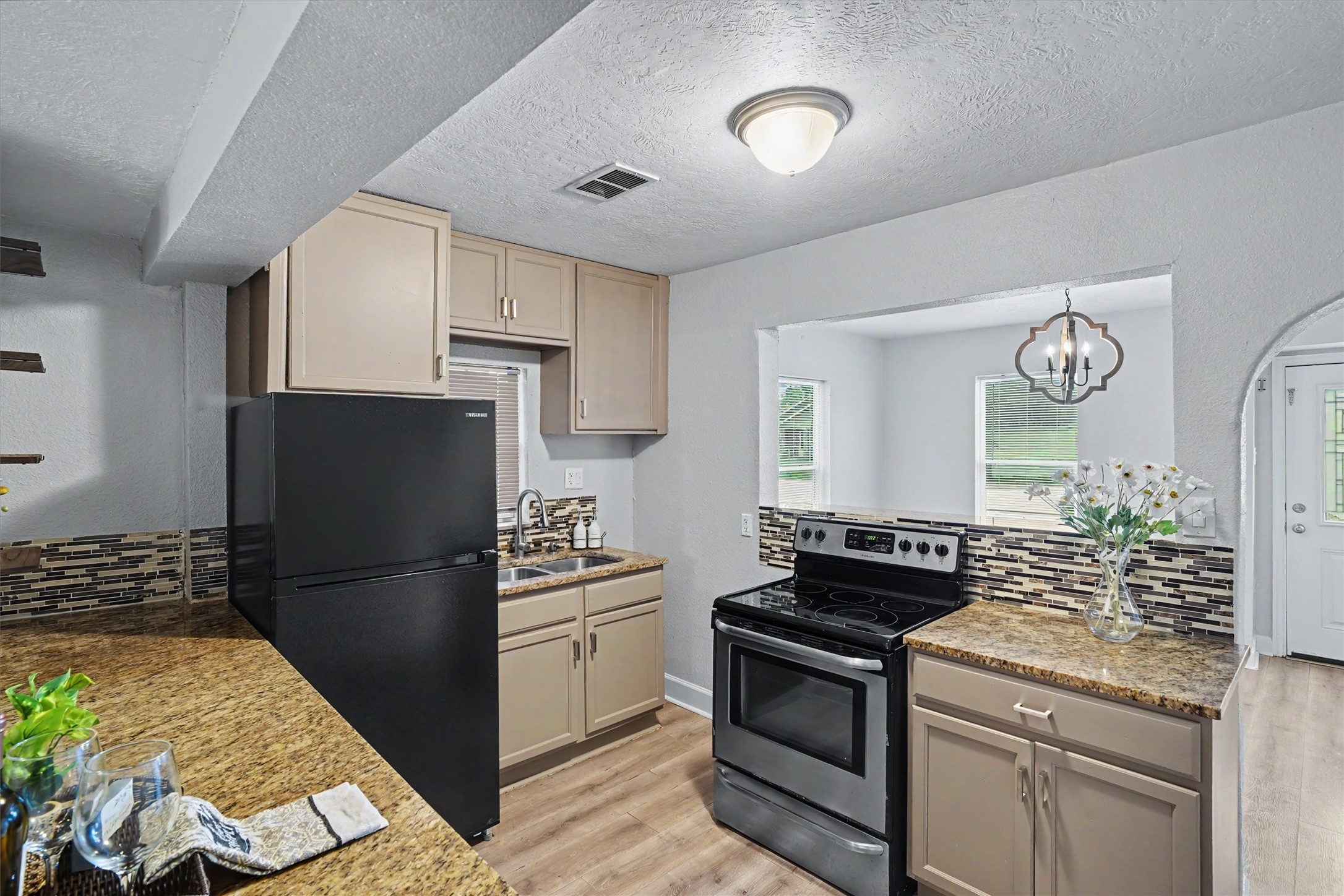 Kitchen features granite countertops, refinished cabinetry, tile backsplash and a convenient breakfast bar overlooking the adjoining living spaces.