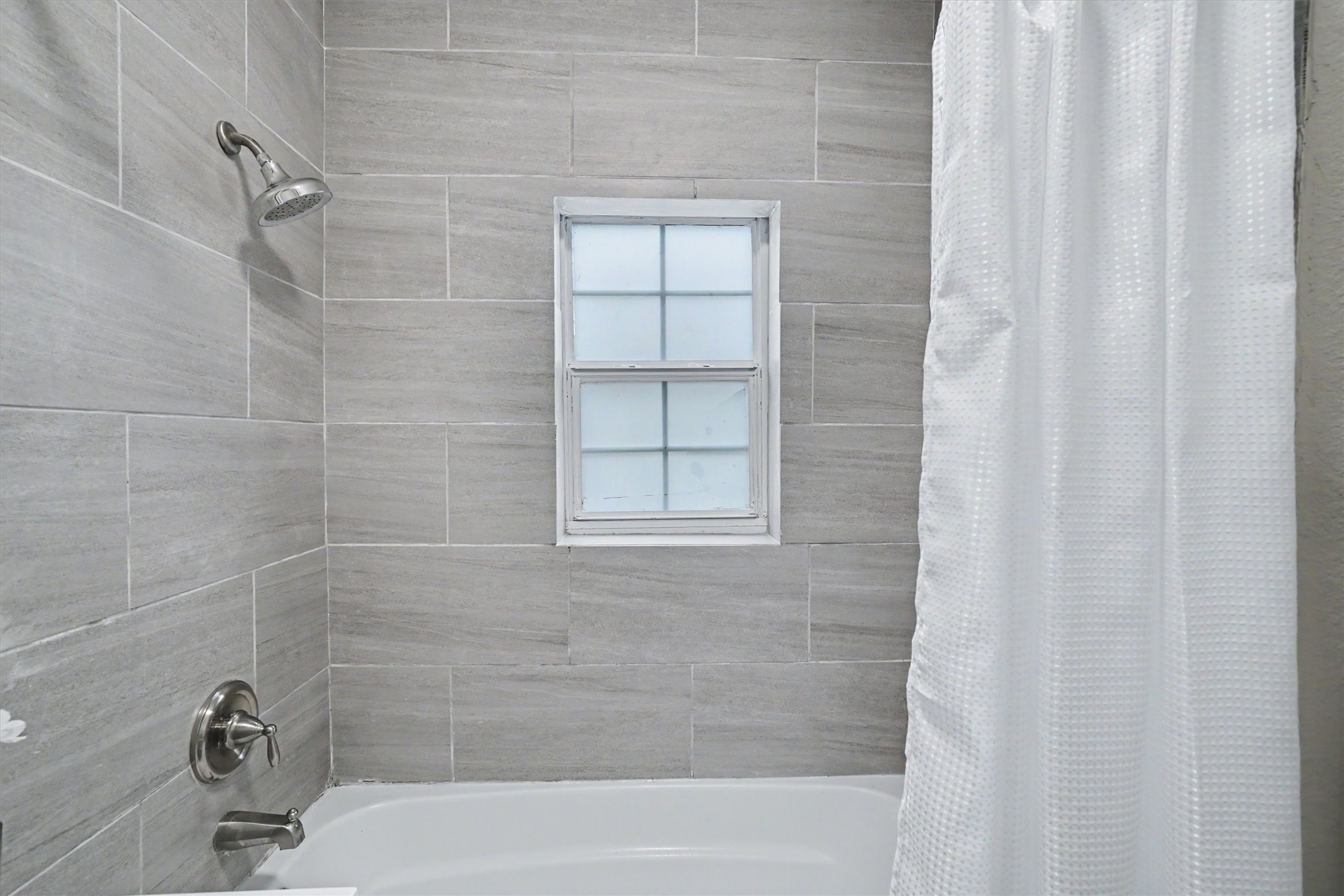 Updated primary bath features a tub/shower combination with tiled surround.